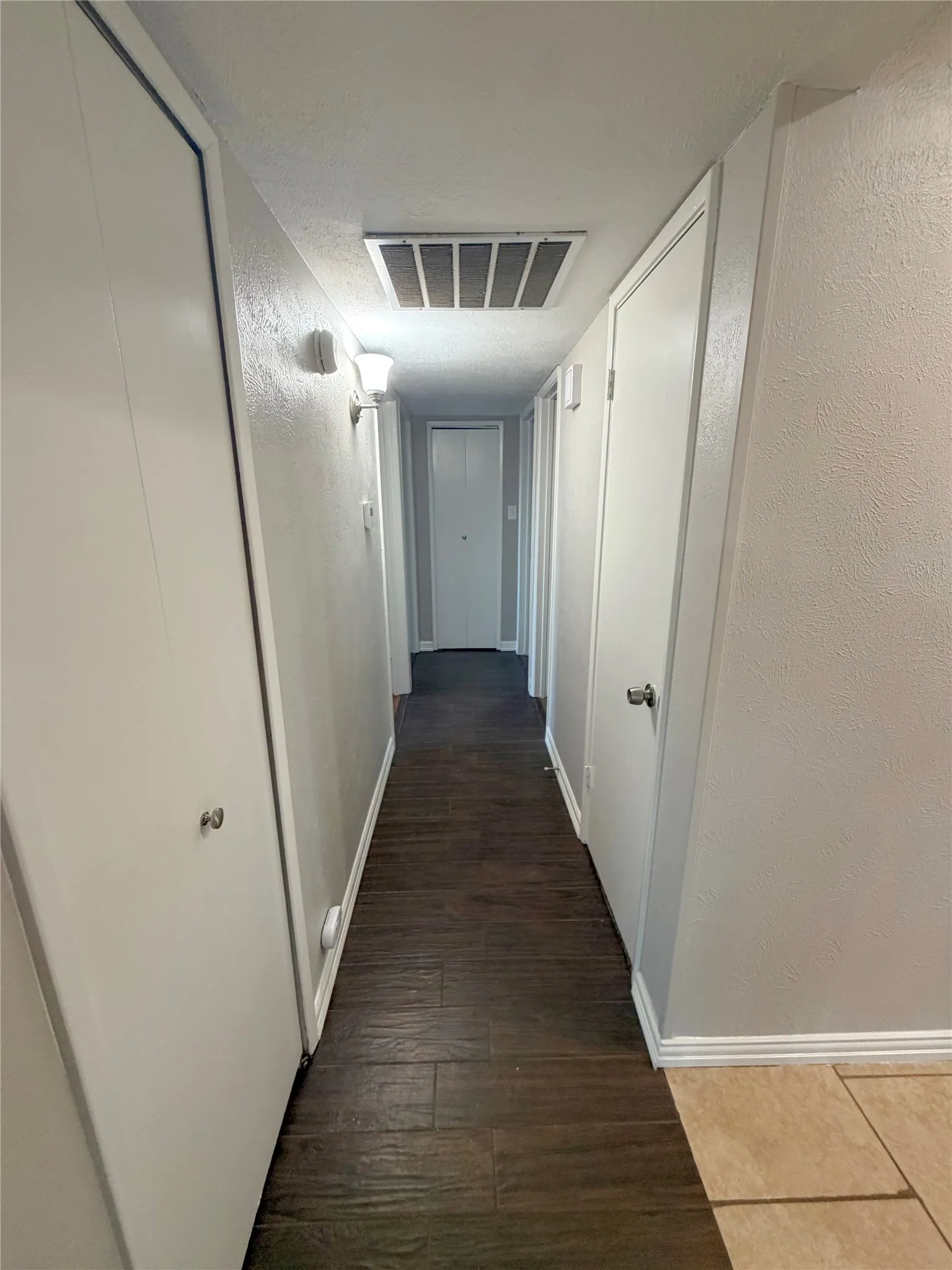 Hallway featuring wood-finish flooring, light grey painted walls, and white trim