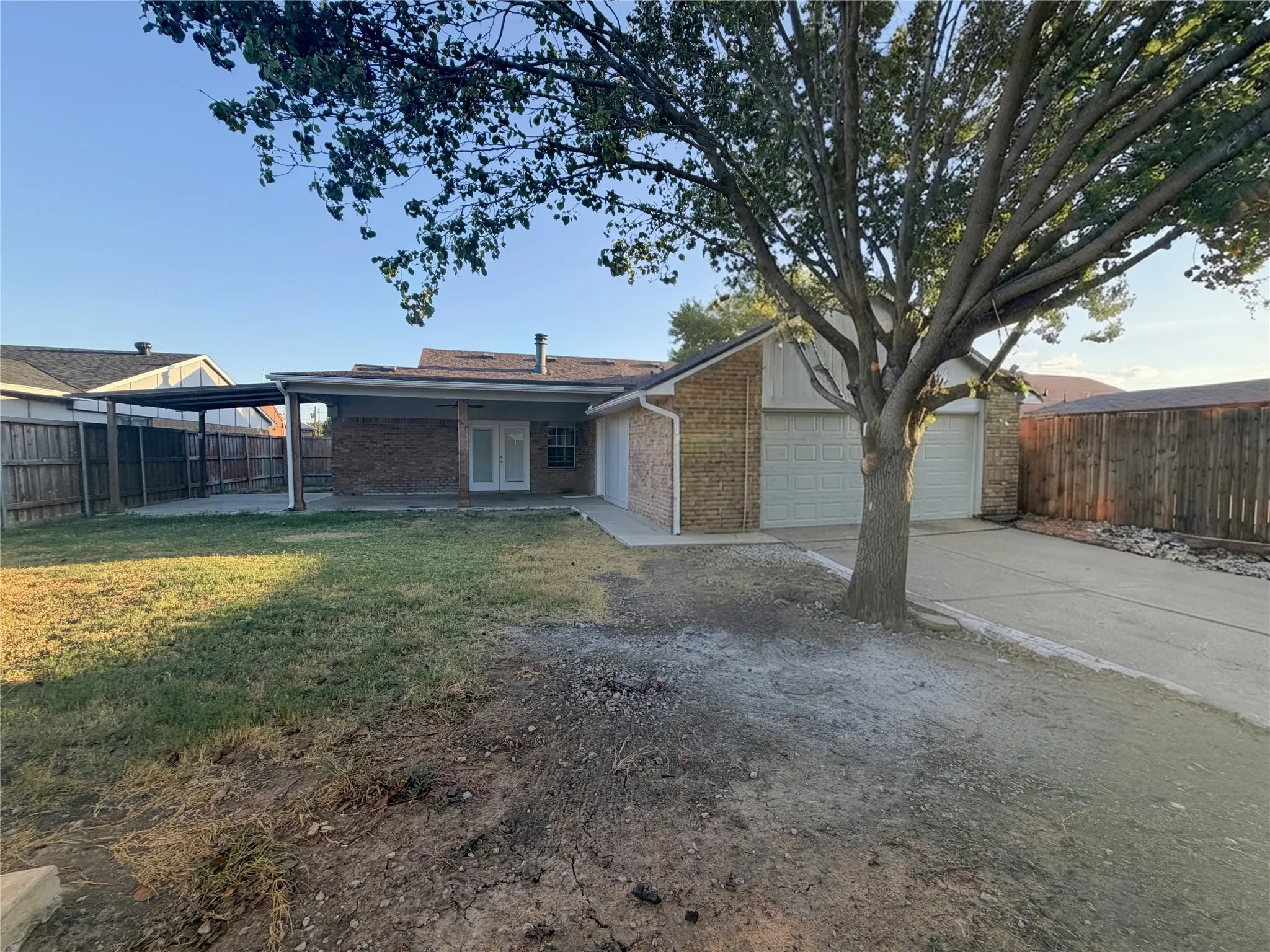 Brick exterior, two-car garage, covered patio, privacy fencing, and concrete driveway