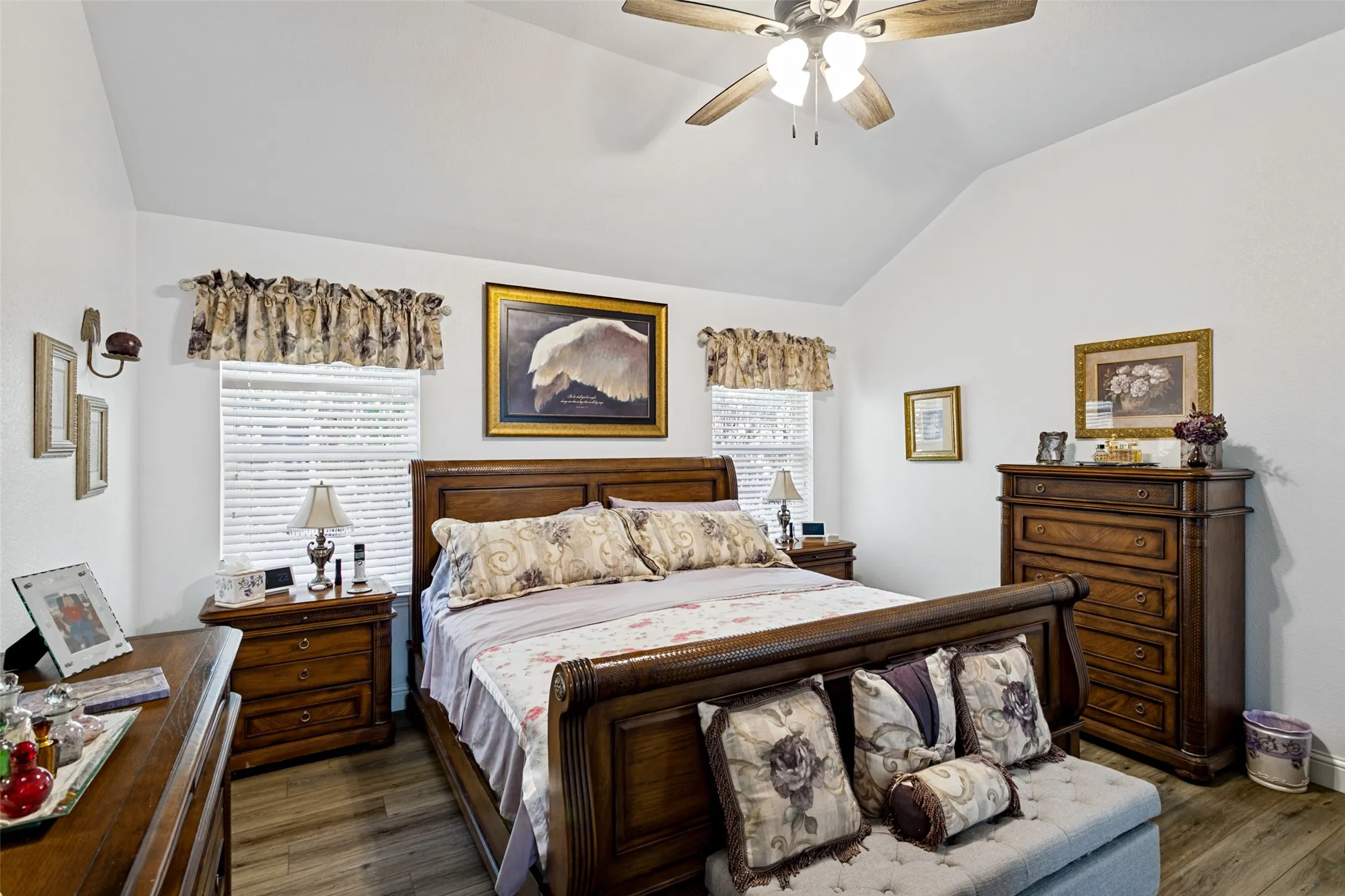 Vaulted ceiling with a ceiling fan, wood-finish flooring, and natural light from a window with blinds