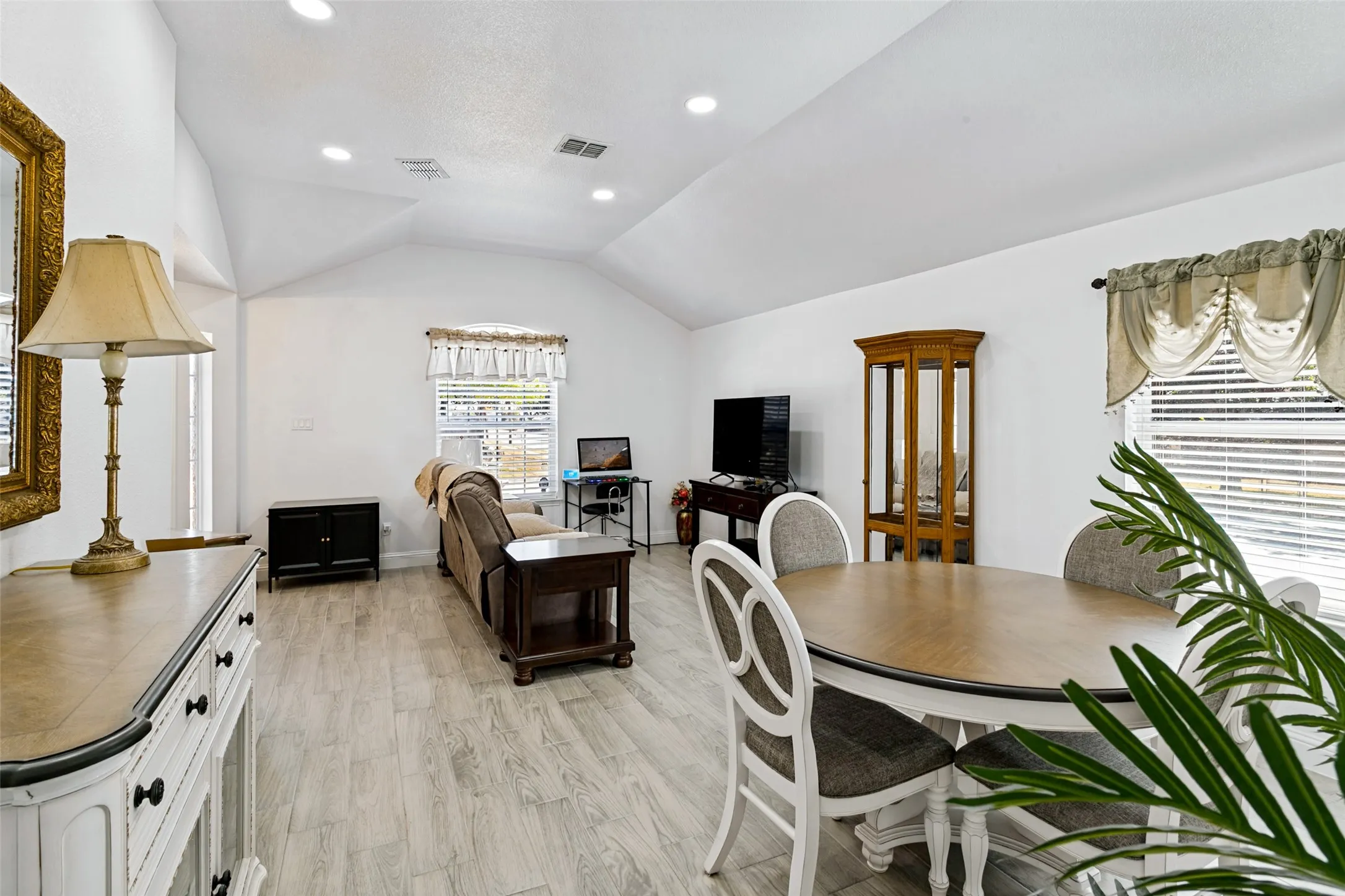 Vaulted ceilings, recessed lighting, wood-finish flooring, and white walls