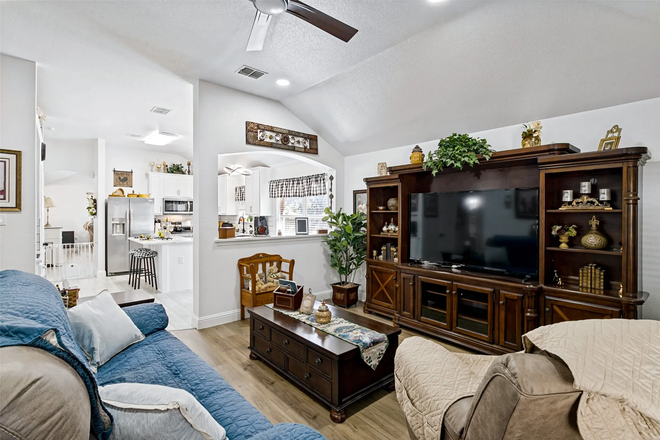 Vaulted ceilings, wood-finish flooring, recessed lighting, and a ceiling fan