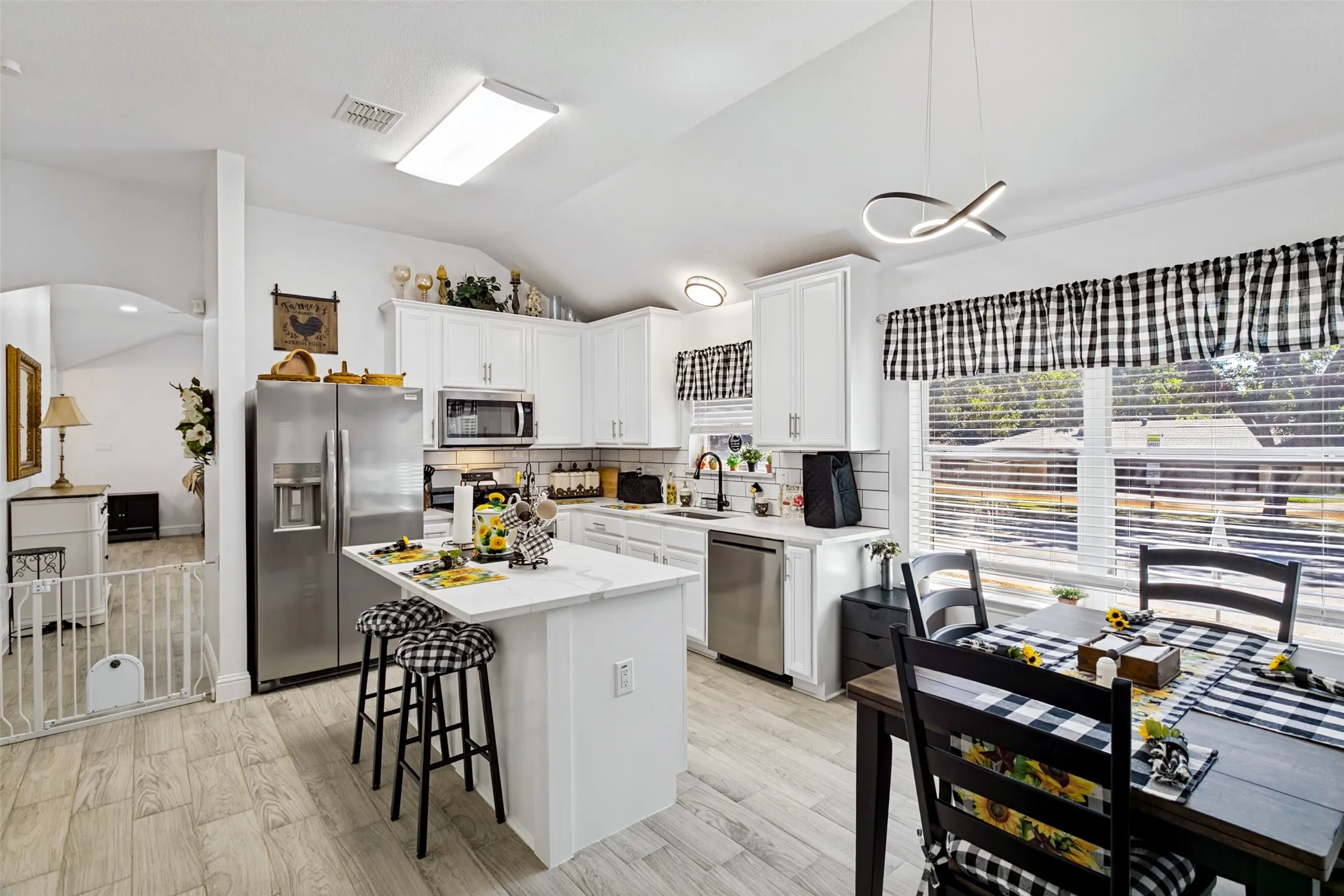 Kitchen featuring white cabinetry, stainless steel appliances, a center island with countertop seating, and wood-finish flooring
