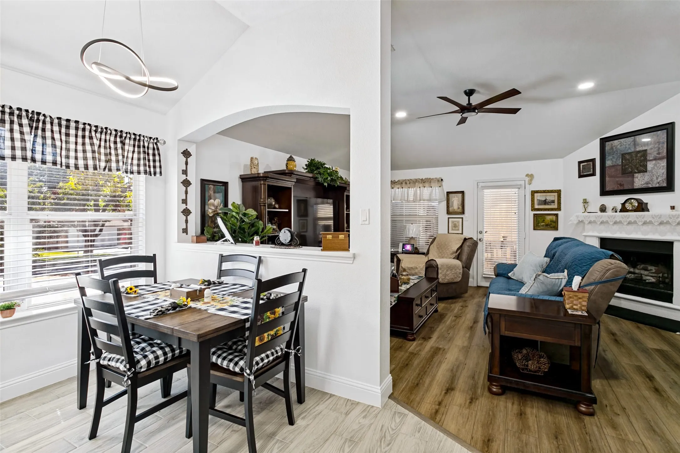 Vaulted ceilings, a built-in fireplace, recessed lighting, wood-finish flooring, and a modern dining light fixture
