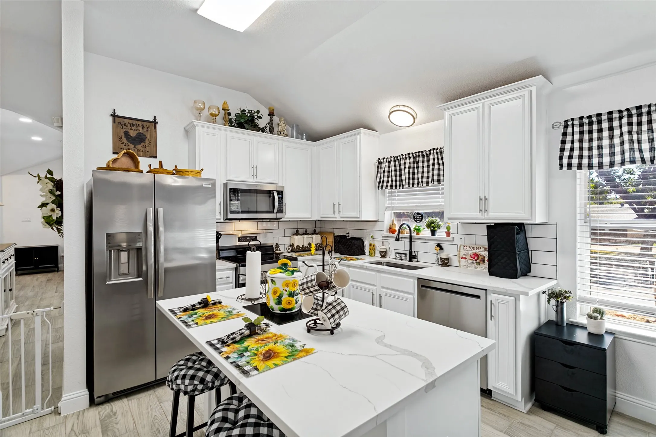 Kitchen featuring white shaker cabinetry, stainless steel appliances, a white subway tile backsplash, and a center island with a white countertop