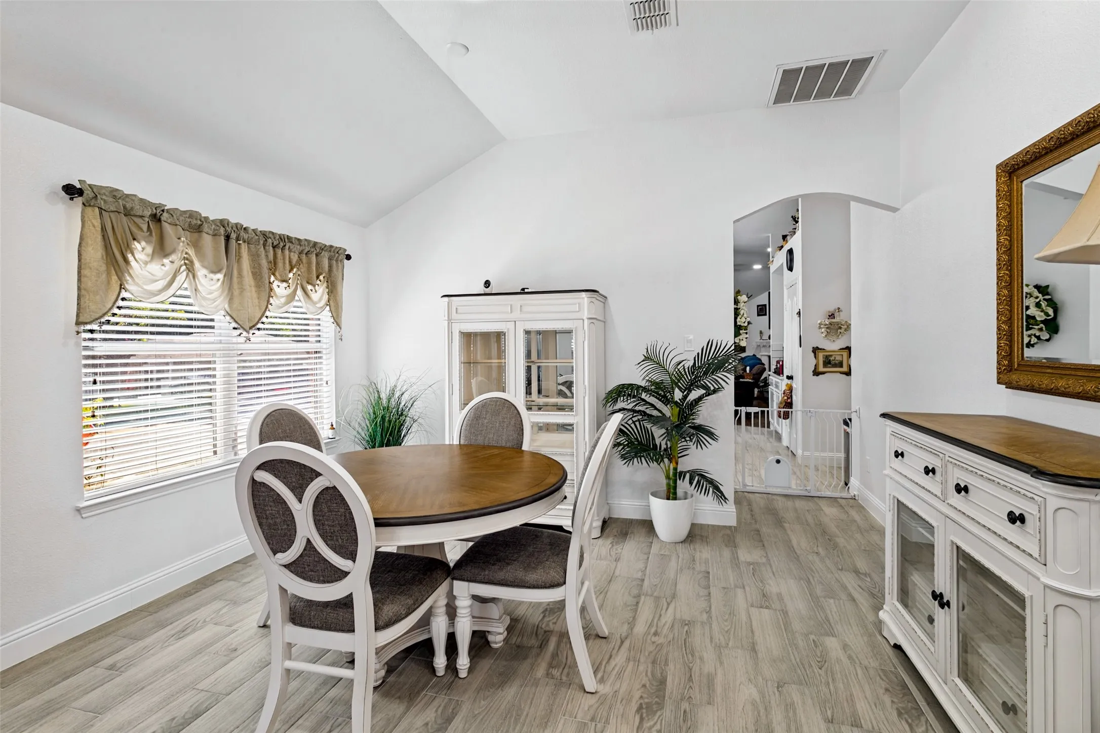 Vaulted ceiling, wood-finish flooring, and white walls