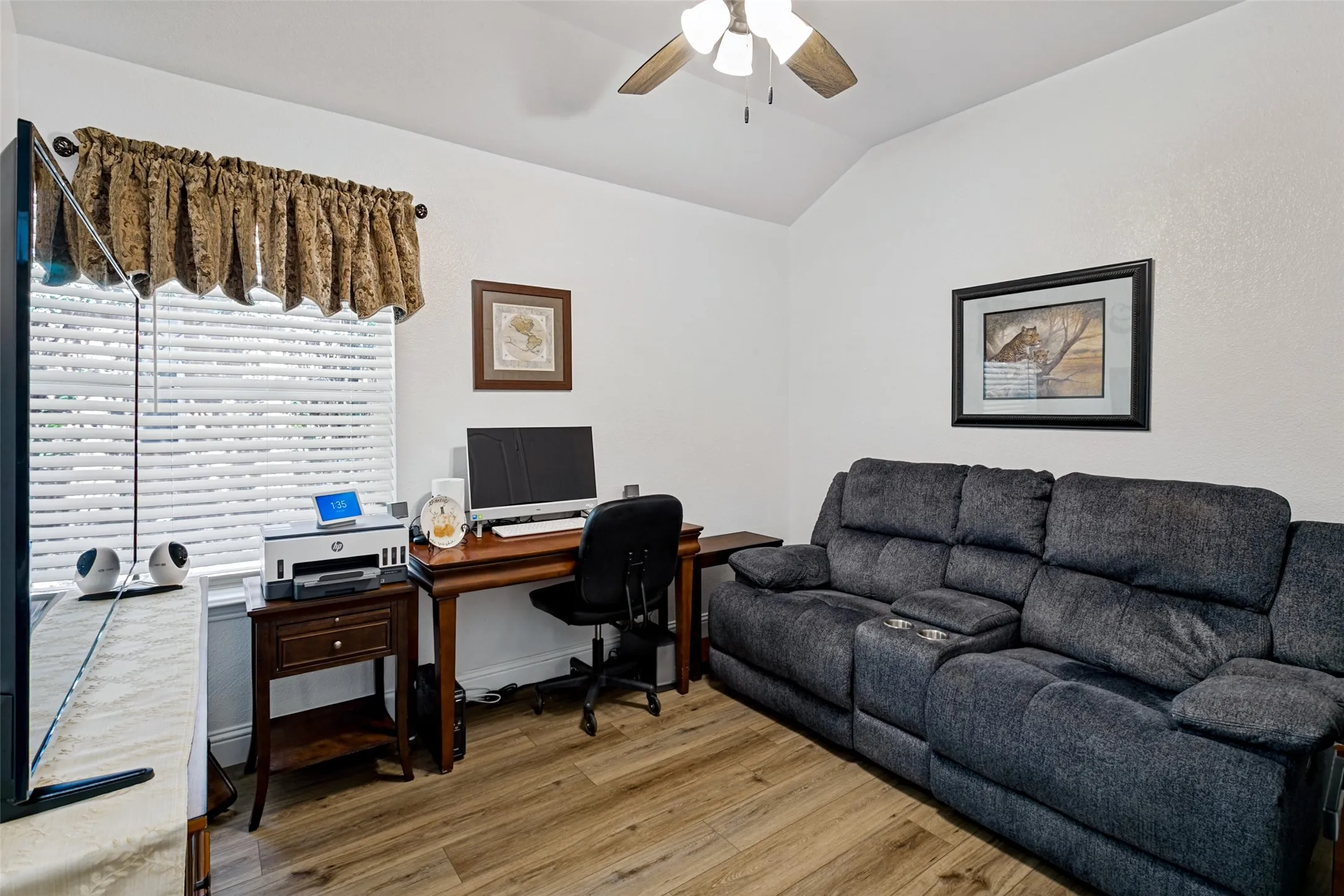 Vaulted ceiling with a ceiling fan, wood-finish flooring, and window with blinds