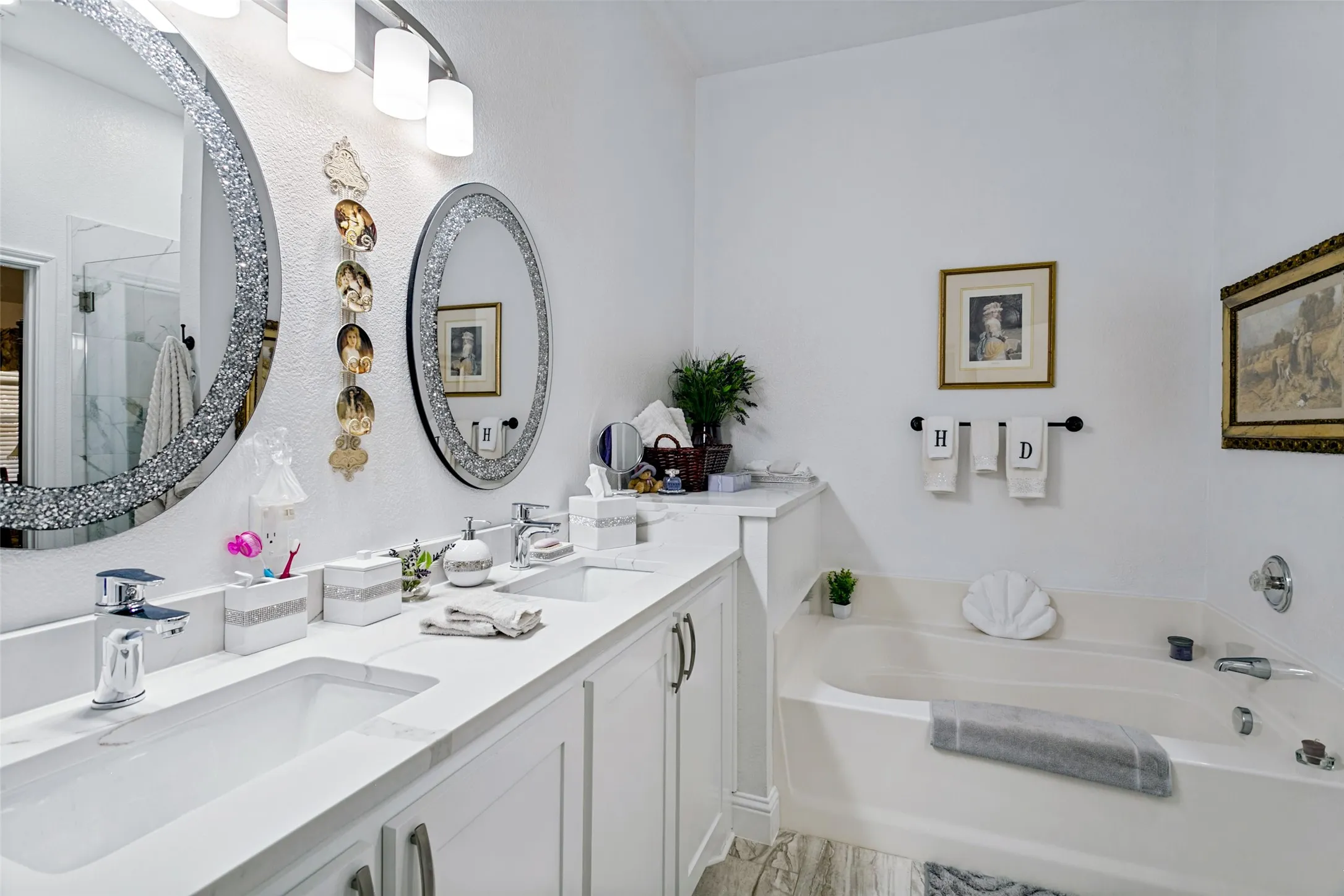 Dual vanity with undermount sinks and chrome fixtures, white cabinetry, and a built-in tub
