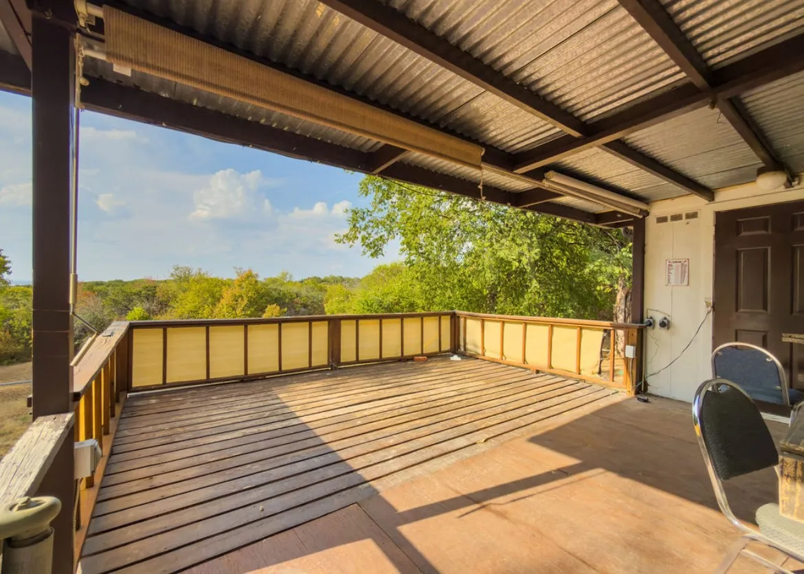 Covered outdoor deck with corrugated metal roofing, exposed wood framing, and wood-finish flooring
