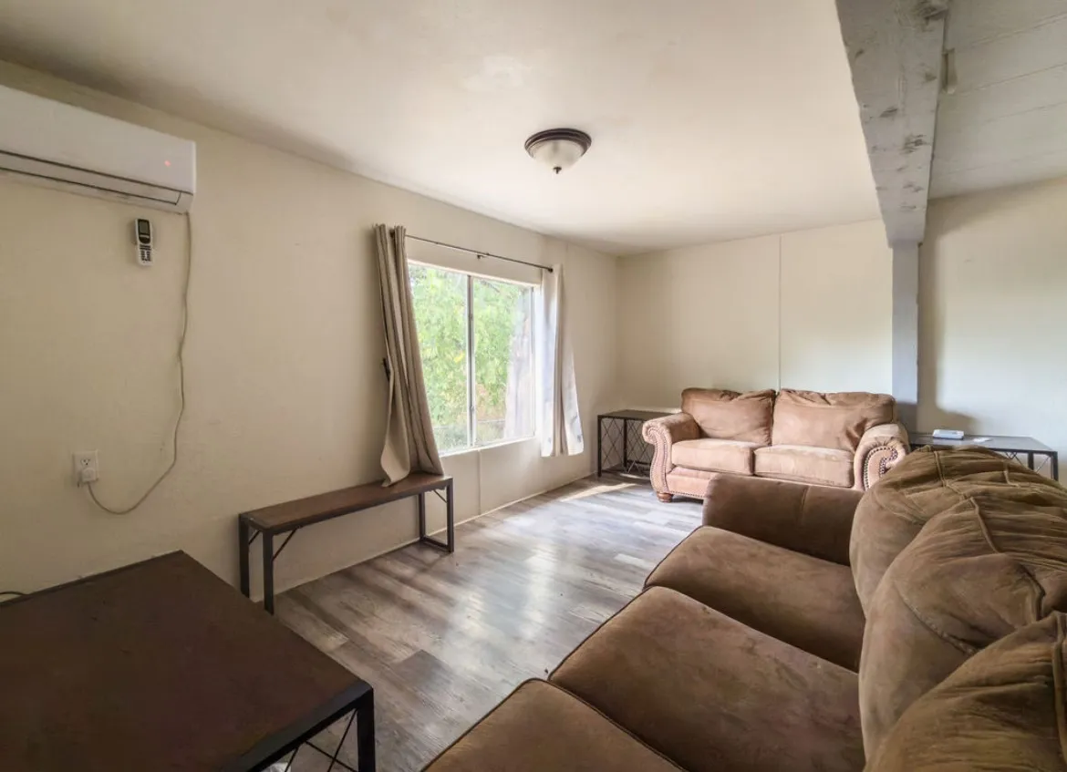 Room featuring wood-finish flooring, a wall-mounted mini-split system, and a window with natural illumination