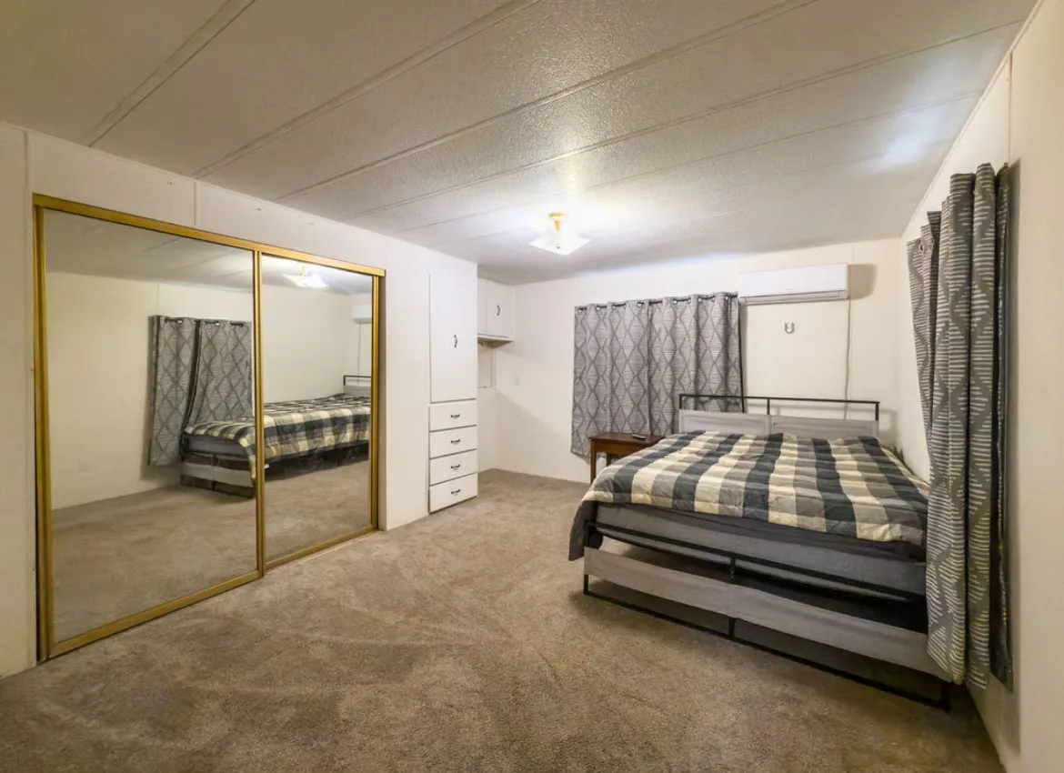 Built-in mirrored sliding closet doors with gold-toned trim, built-in cabinetry with drawers, and carpeted flooring