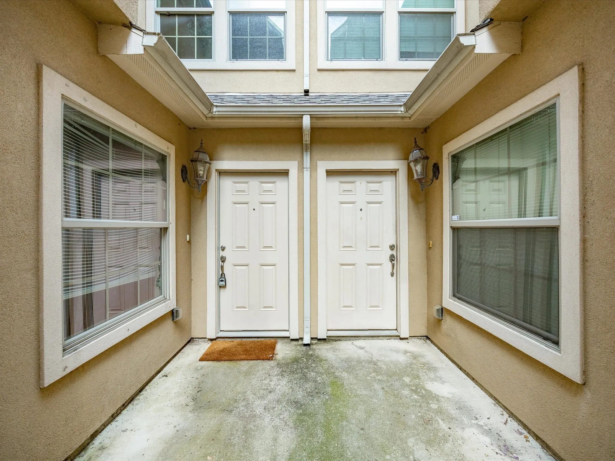 Dual entryways featuring paneled doors and exterior wall sconces