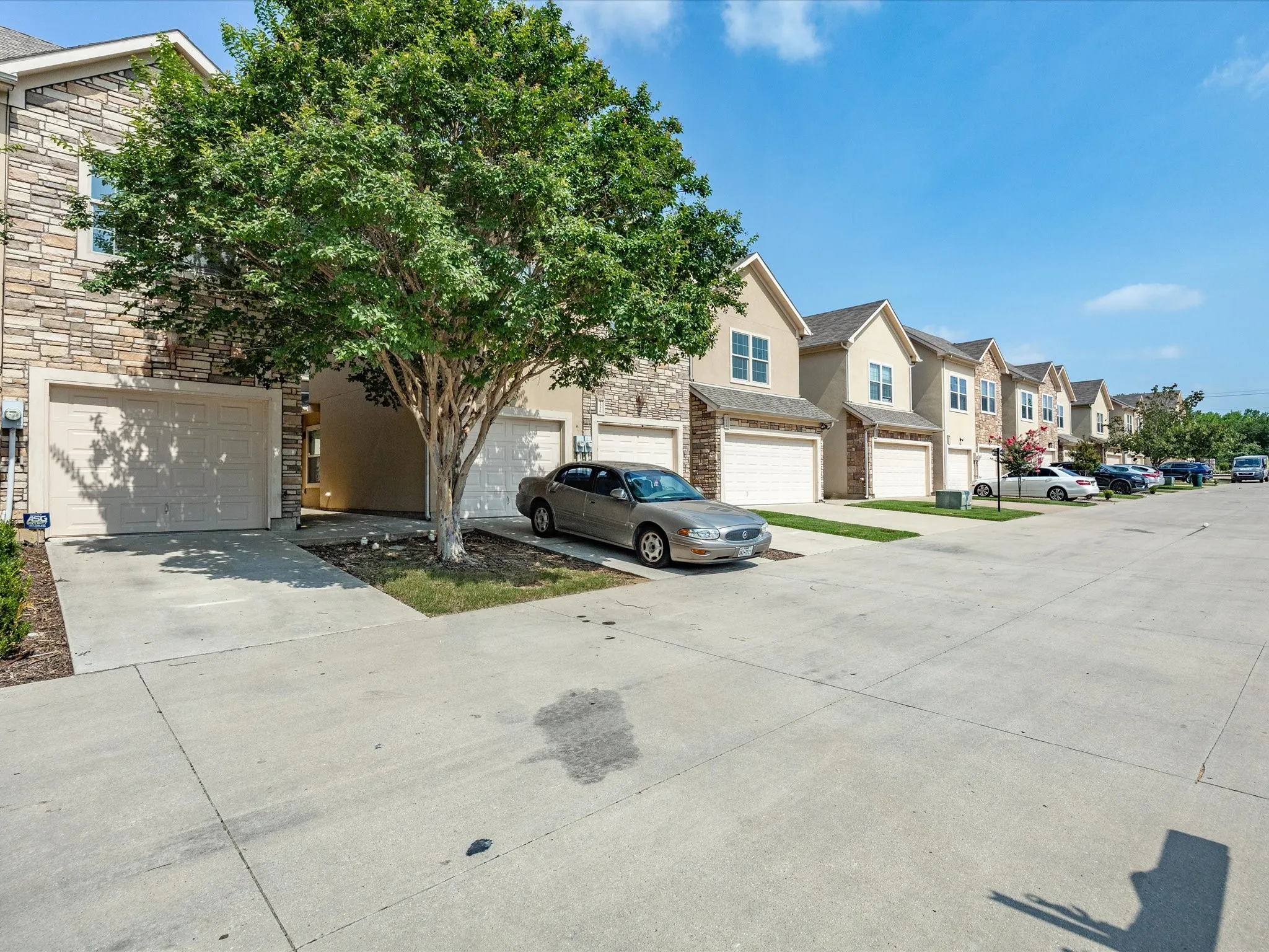 Stone and stucco exterior with multiple windows, an attached garage, and a concrete driveway