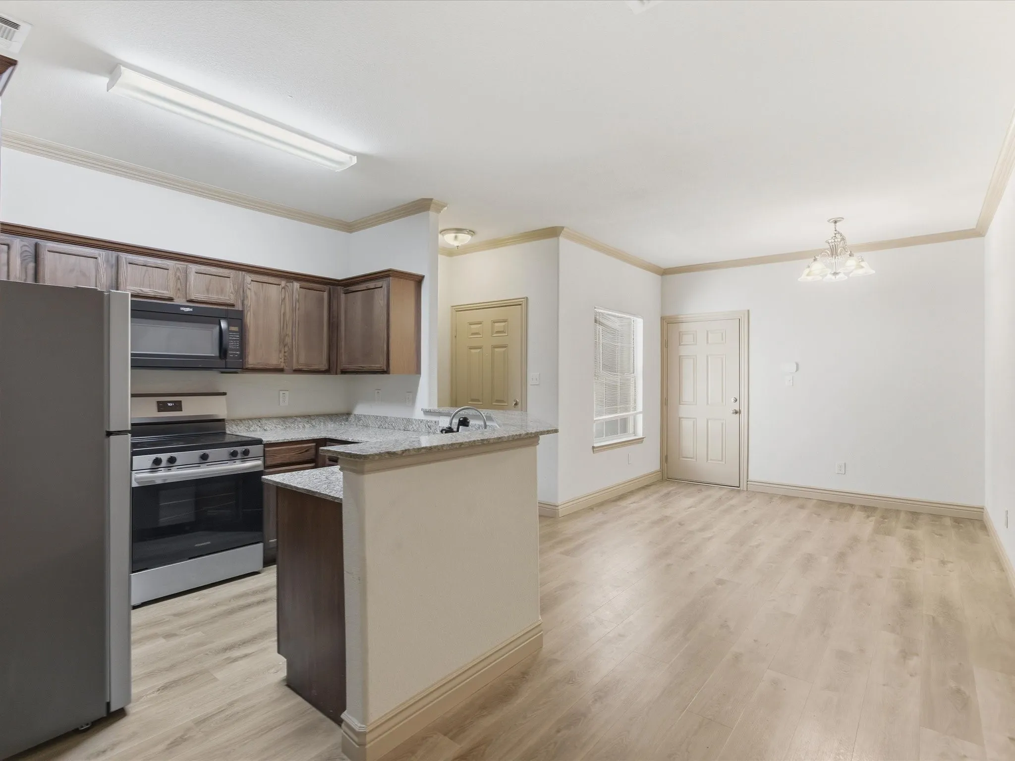 Kitchen featuring wood-finish cabinetry, stainless steel appliances, and granite countertops