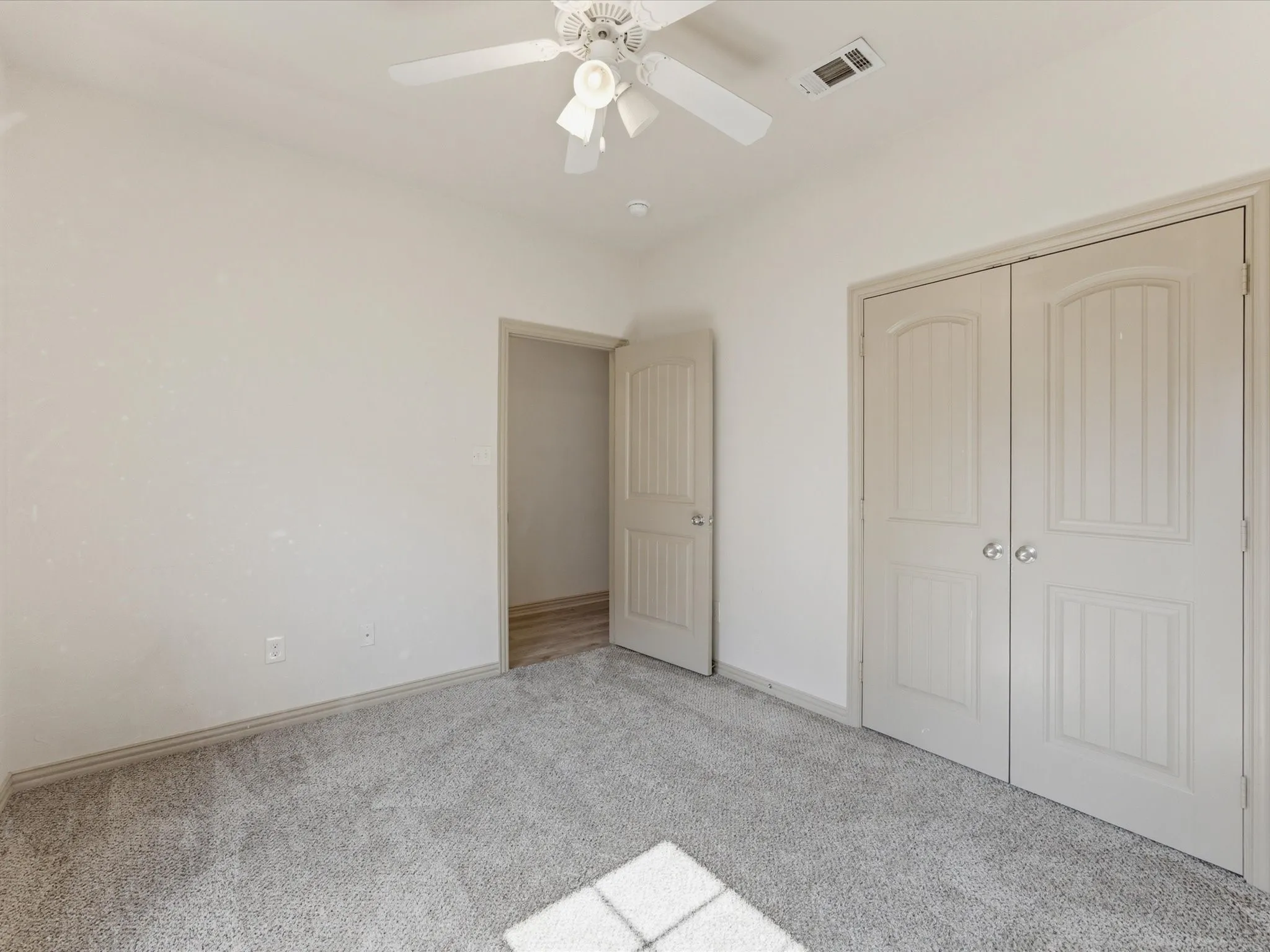 Wall-to-wall carpeting, overhead ceiling fan, and double-door closet