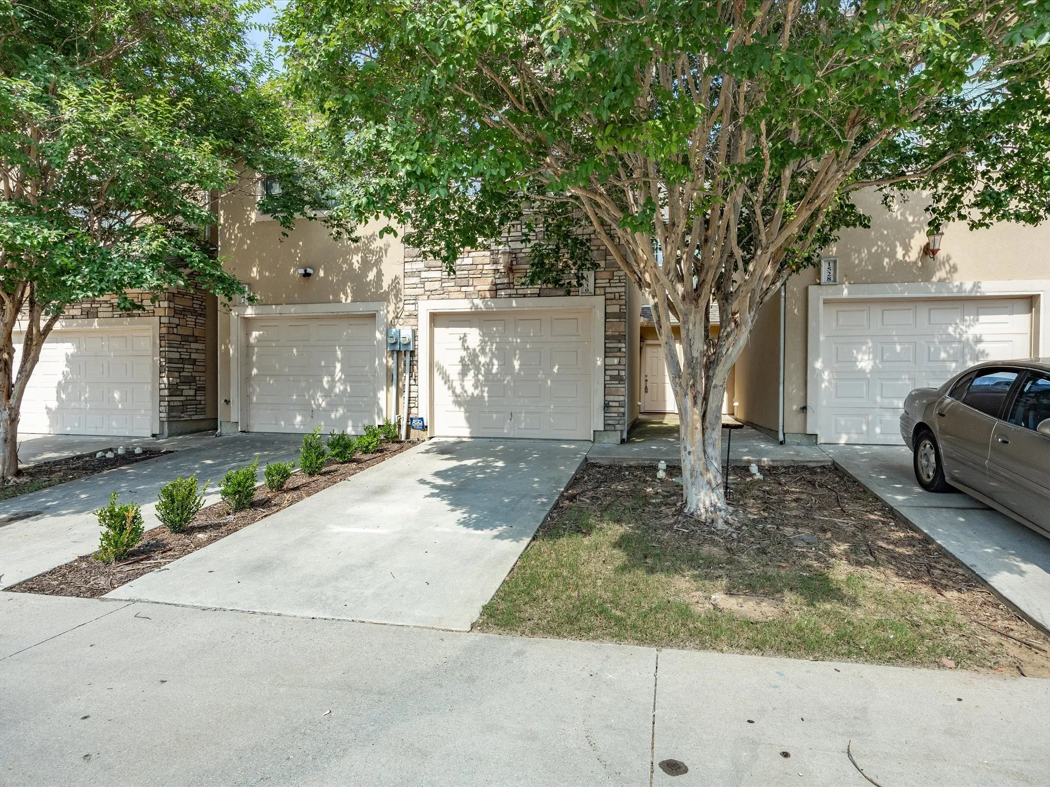 Stone and stucco exterior facade with individual garage doors and concrete driveways