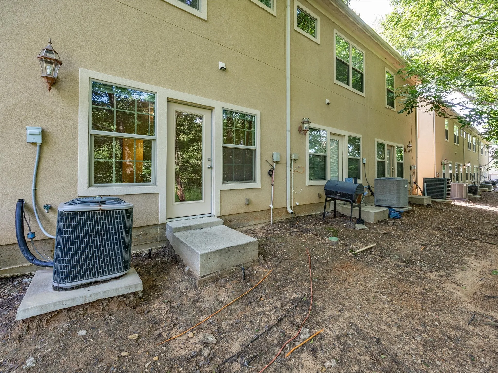 Exterior wall with multiple windows, a glass-paneled door, and a concrete step