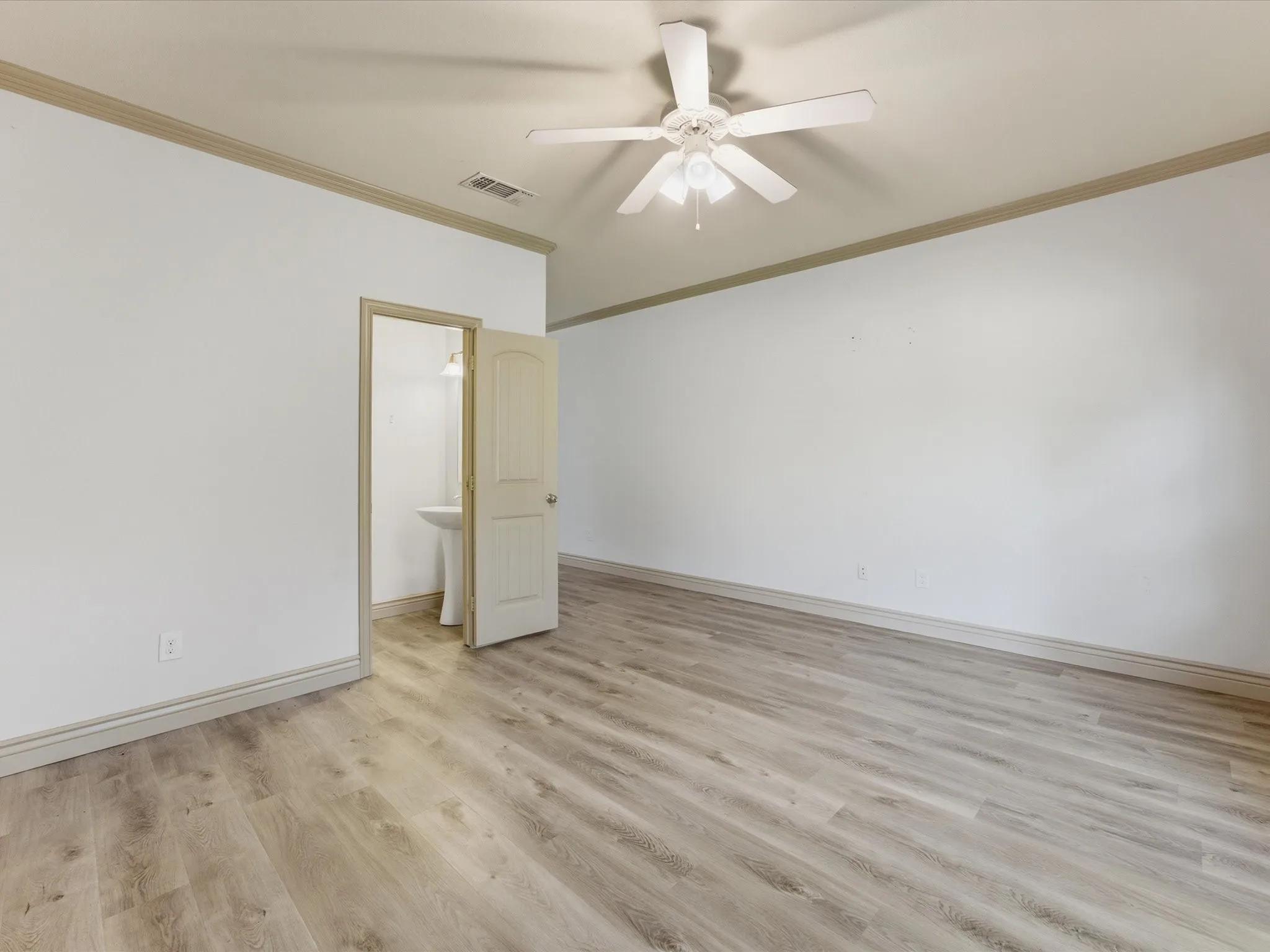 Wood-finish flooring, ceiling fan, crown molding, and an attached pedestal sink