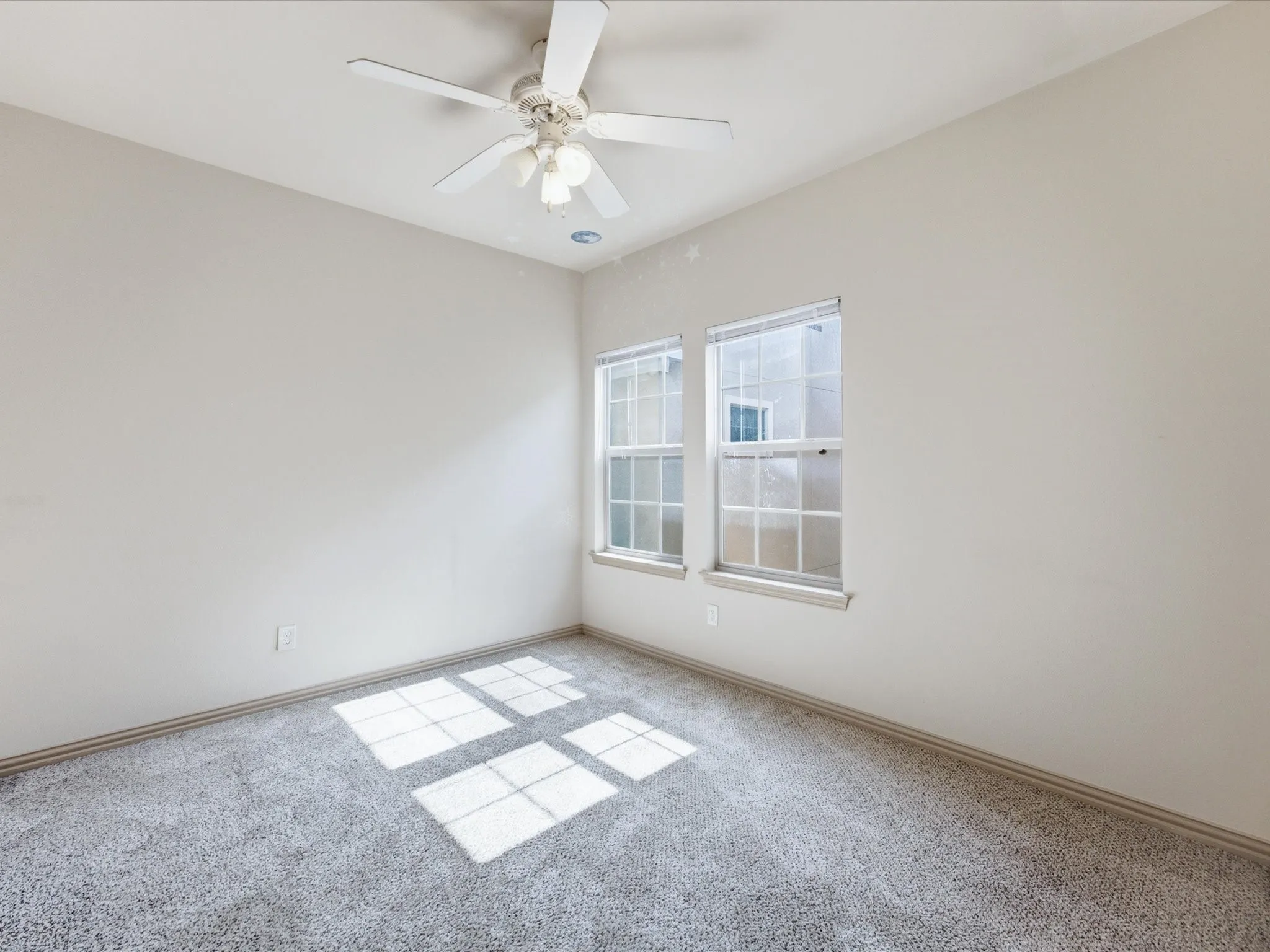 Carpeted room featuring two windows and a ceiling fan