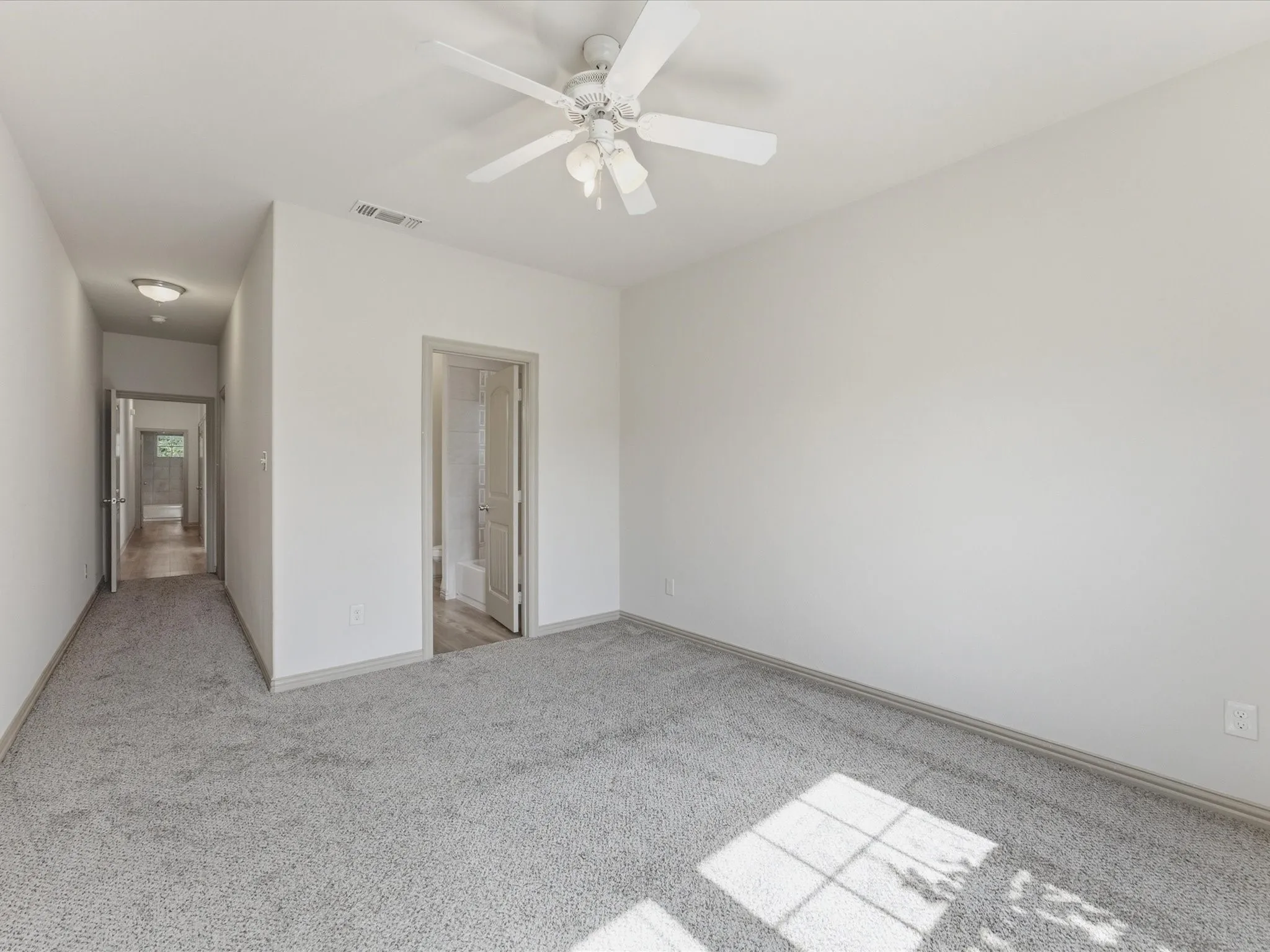 Plush gray carpeting throughout, white painted walls, and a ceiling fan with integrated lighting