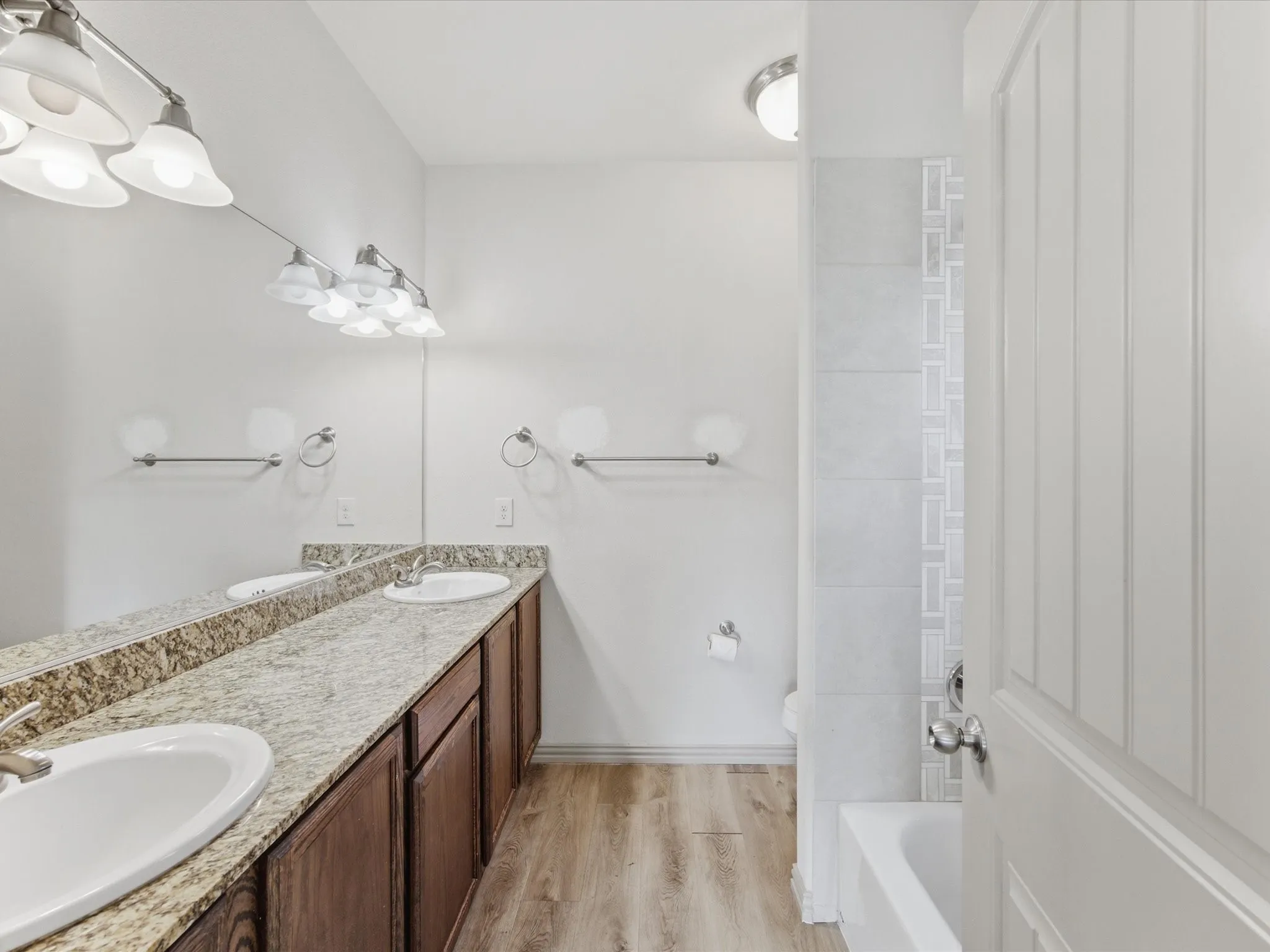 Dual vanity with light-toned countertop, wood-finish cabinetry, and contemporary fixtures