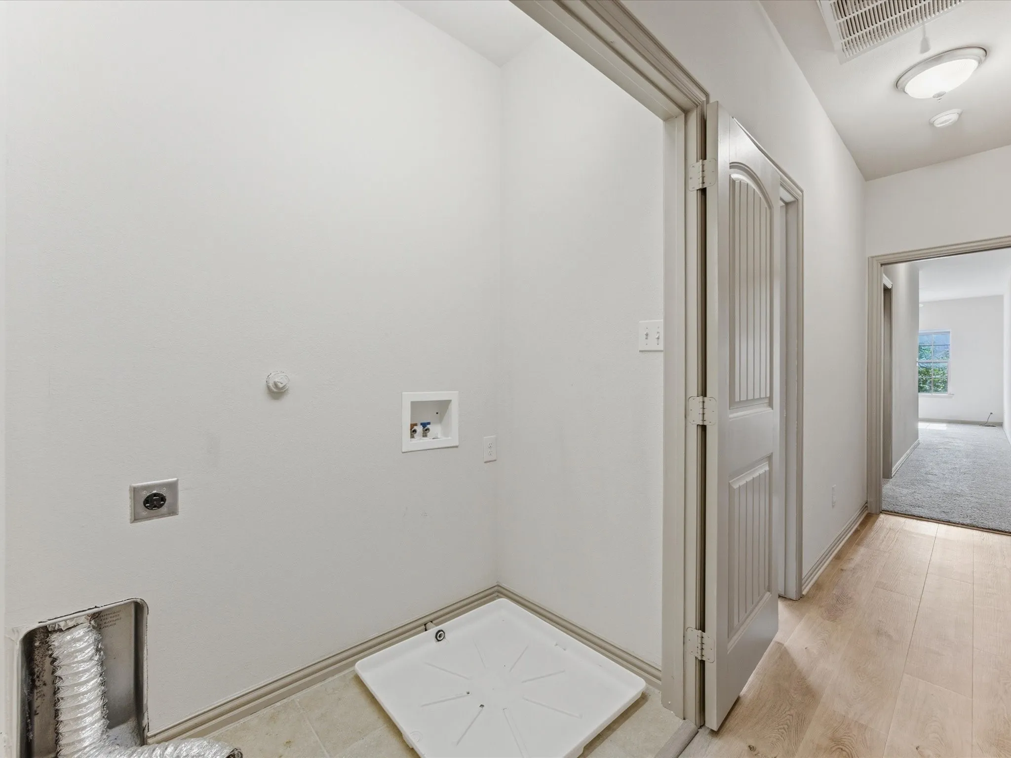 Dedicated laundry area with utility hookups and a protective pan