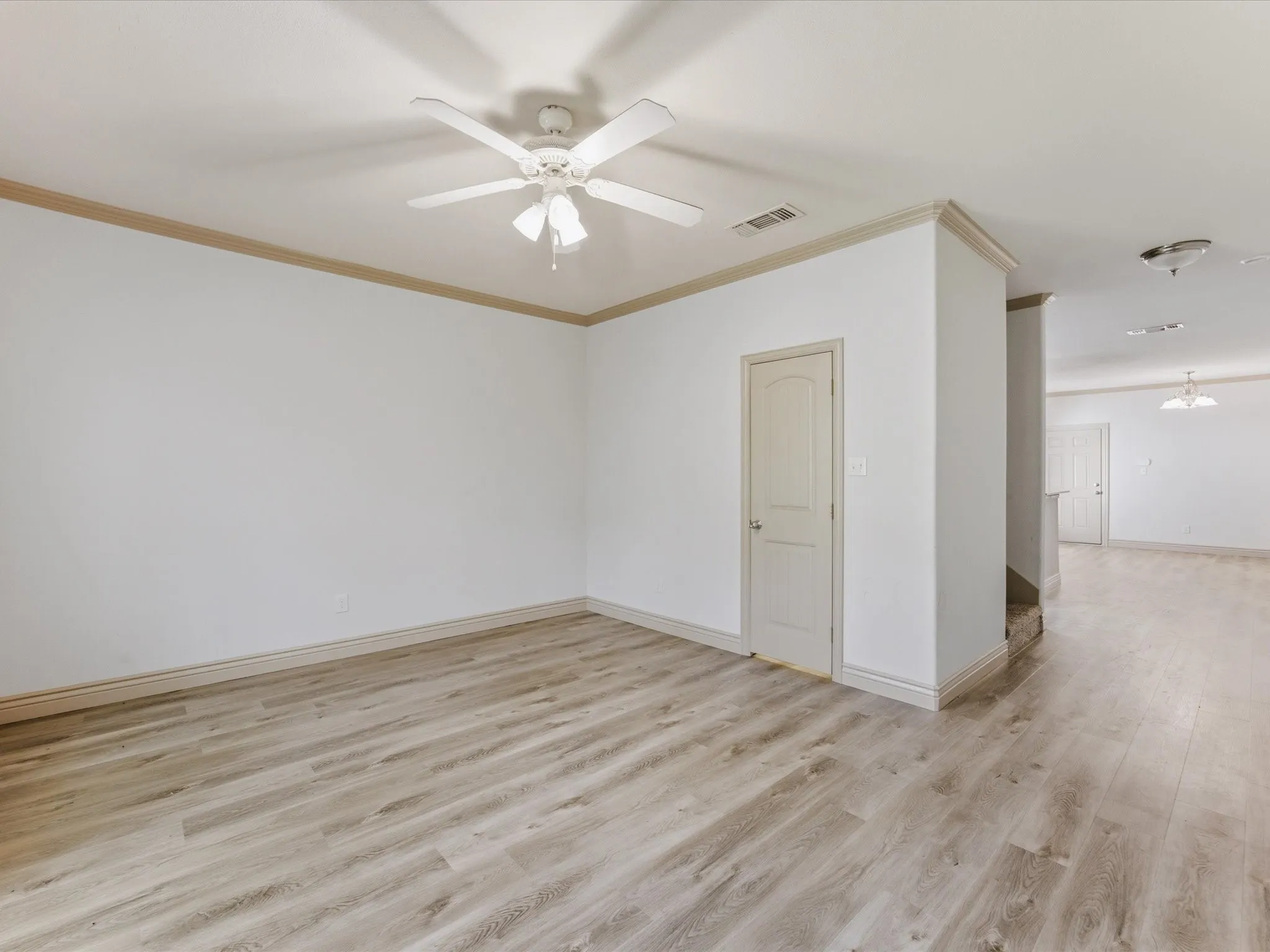 Light wood-finish flooring with white walls and crown molding