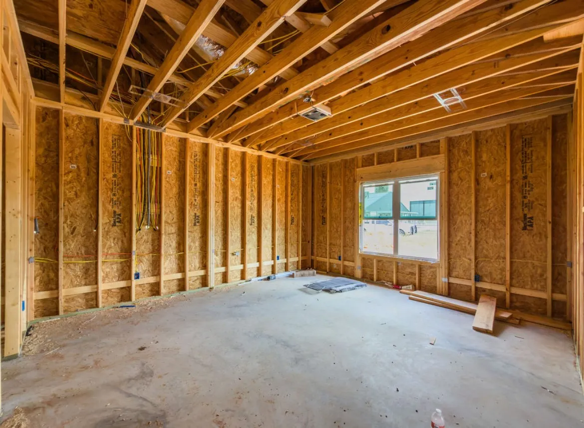 Exposed wood framing, concrete flooring, and a large window with multiple panes