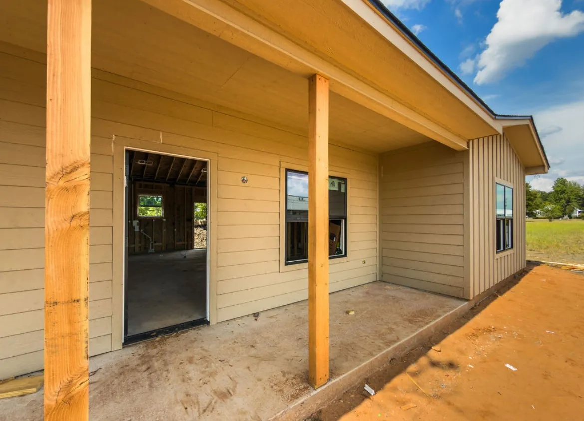 Covered concrete porch with exposed wood columns, horizontal siding, and vertical siding accents