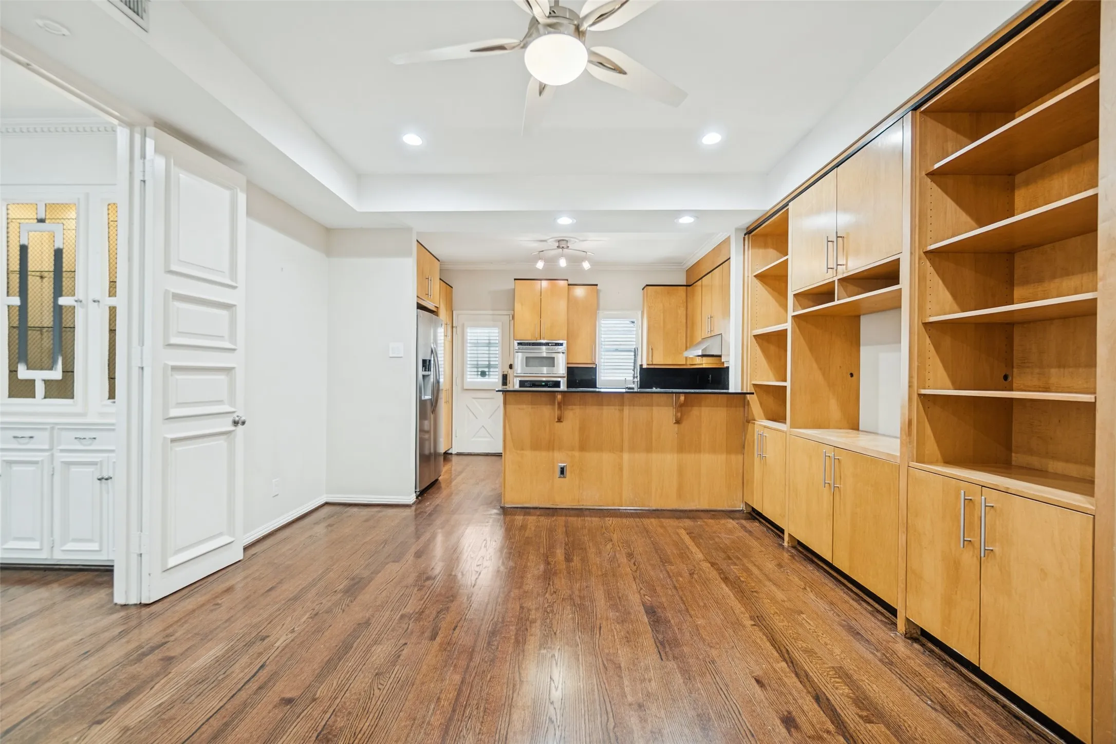 Wood-finish flooring, recessed lighting, ceiling fan, built-in cabinetry, and integrated shelving
