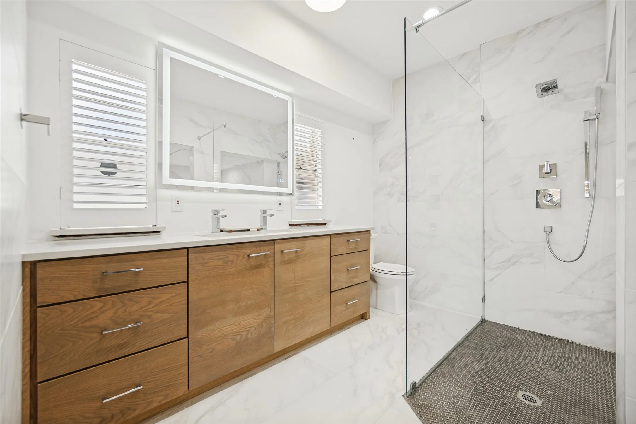 Dual vanity with wood-finish cabinetry, white stone countertop, and two rectangular undermount sinks