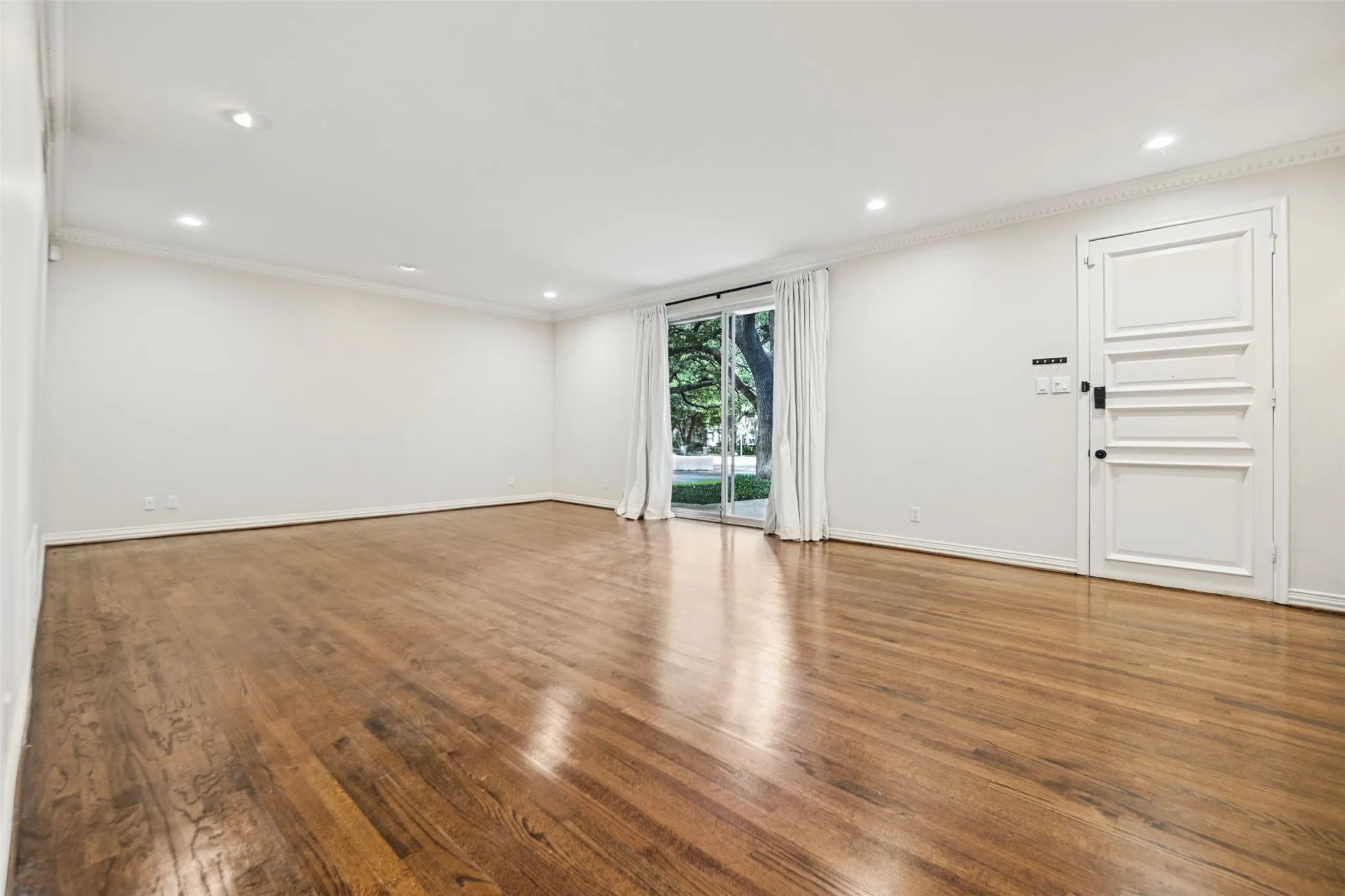 Hardwood flooring, crown molding, recessed lighting, white walls, and a sliding glass door