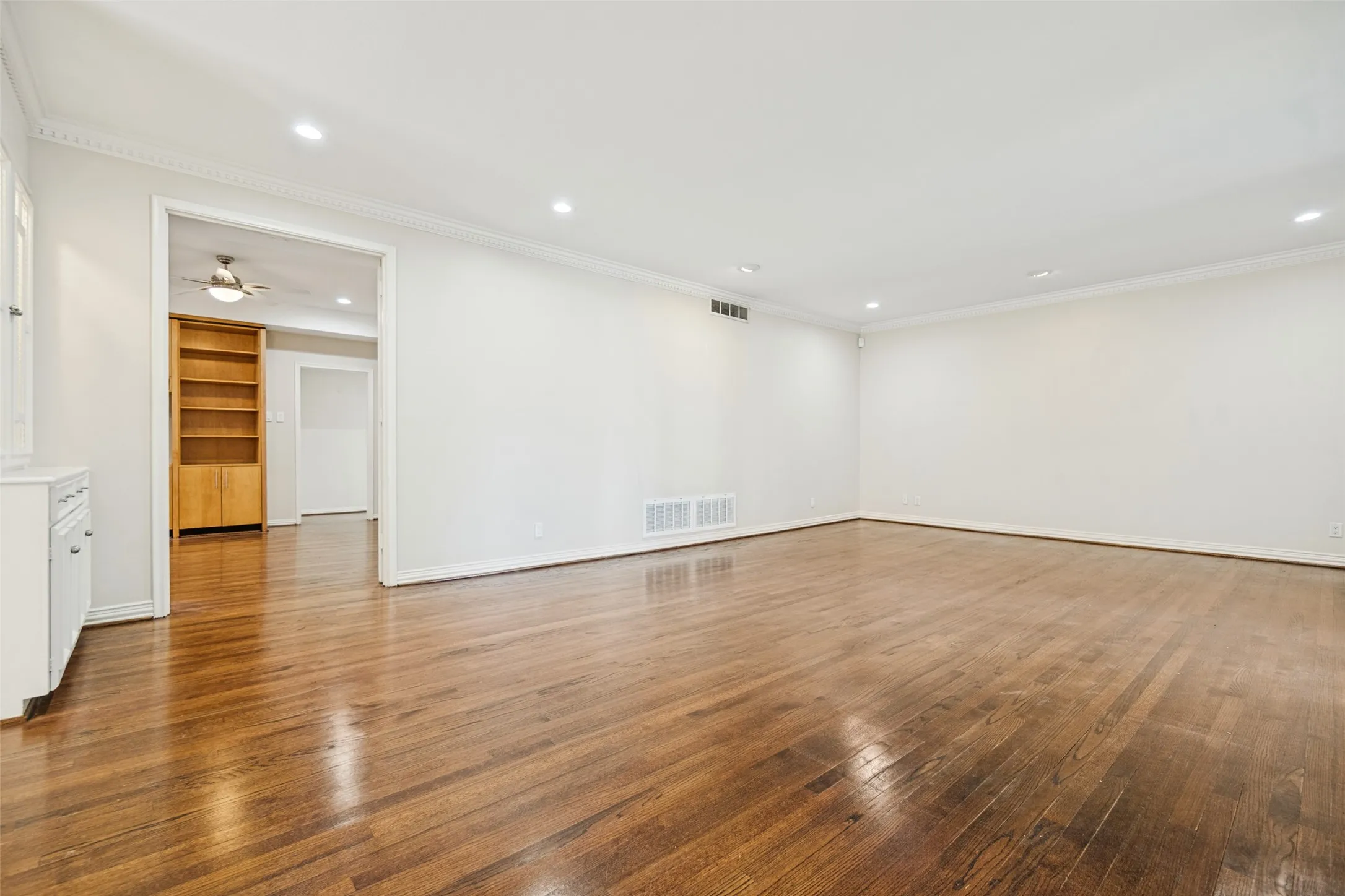 Hardwood flooring, recessed lighting, crown molding, white painted walls, and built-in cabinetry