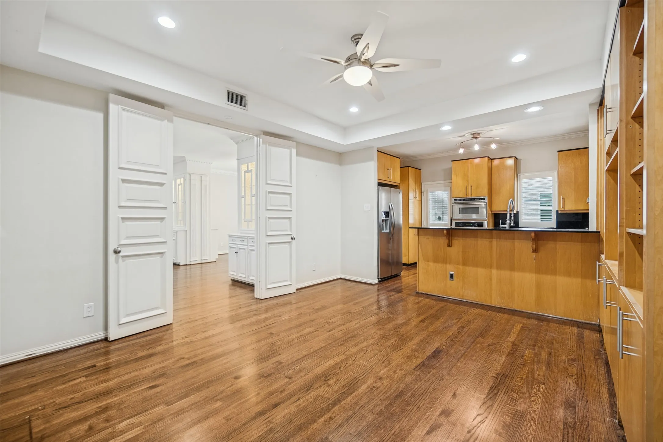 Wood-finish flooring throughout, with a ceiling fan, recessed lighting, and built-in shelving