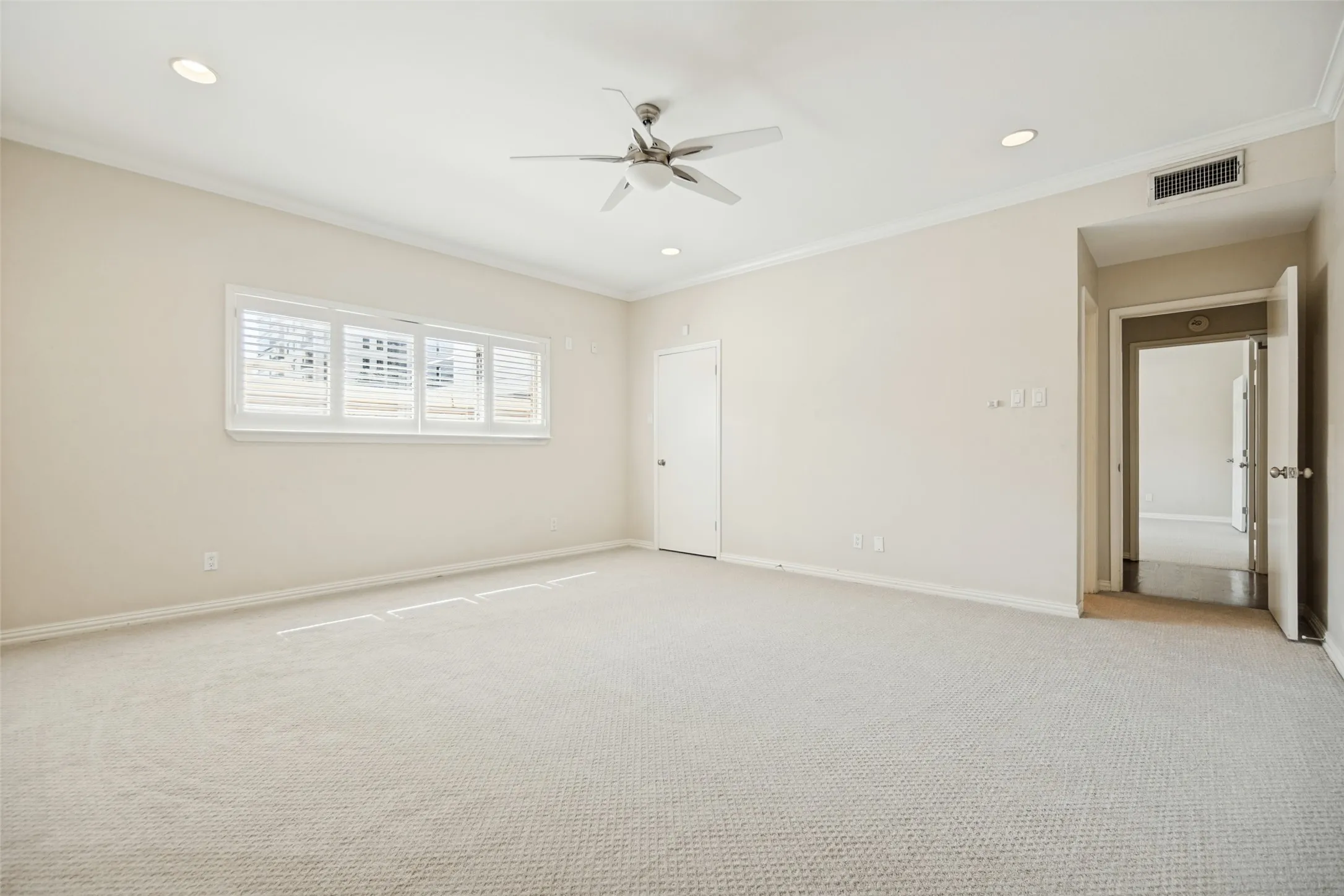 Recessed lighting, crown molding, and neutral-toned carpeting