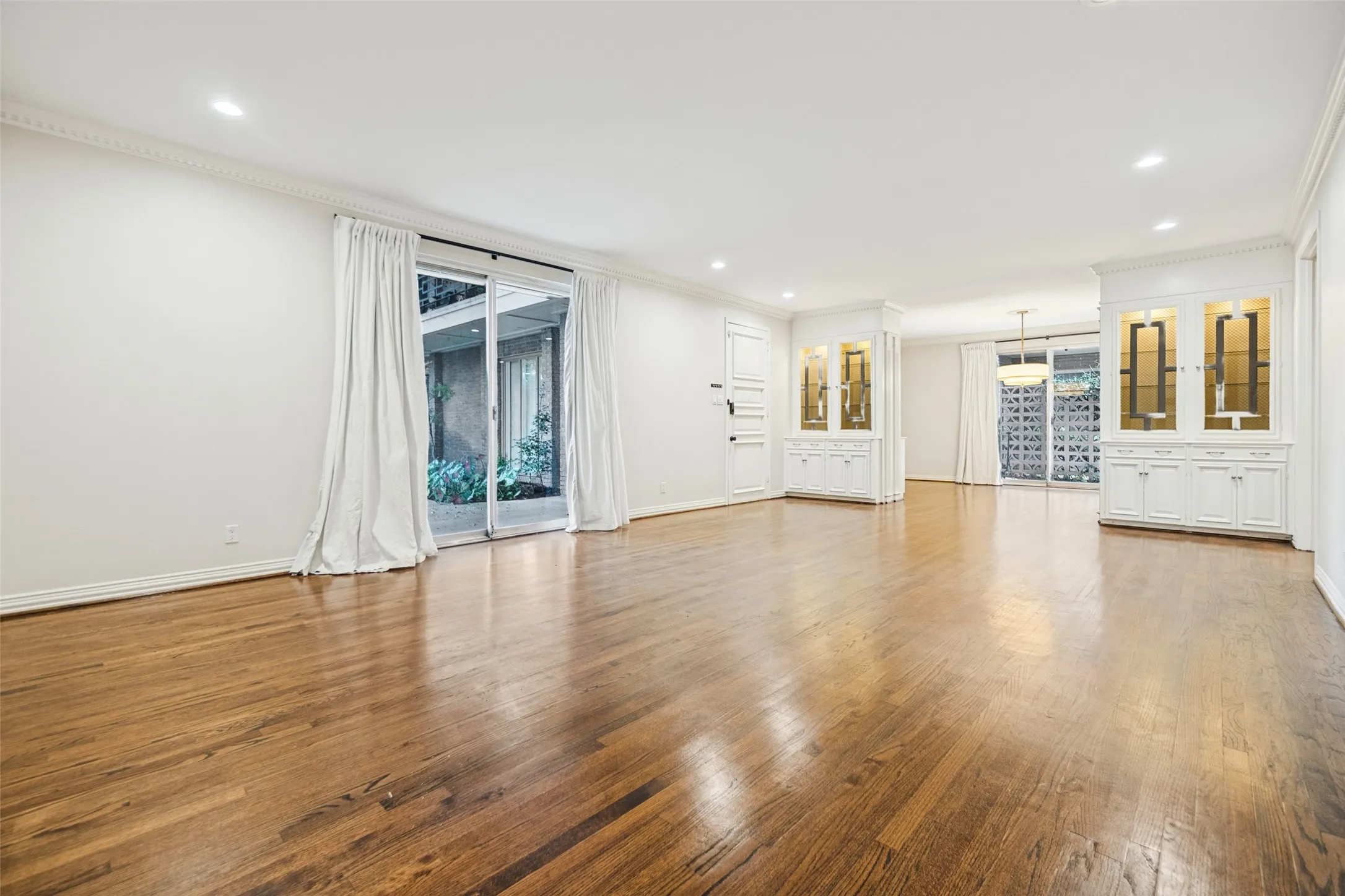 Hardwood flooring throughout, recessed lighting, crown molding, built-in cabinetry with glass display, and sliding glass doors