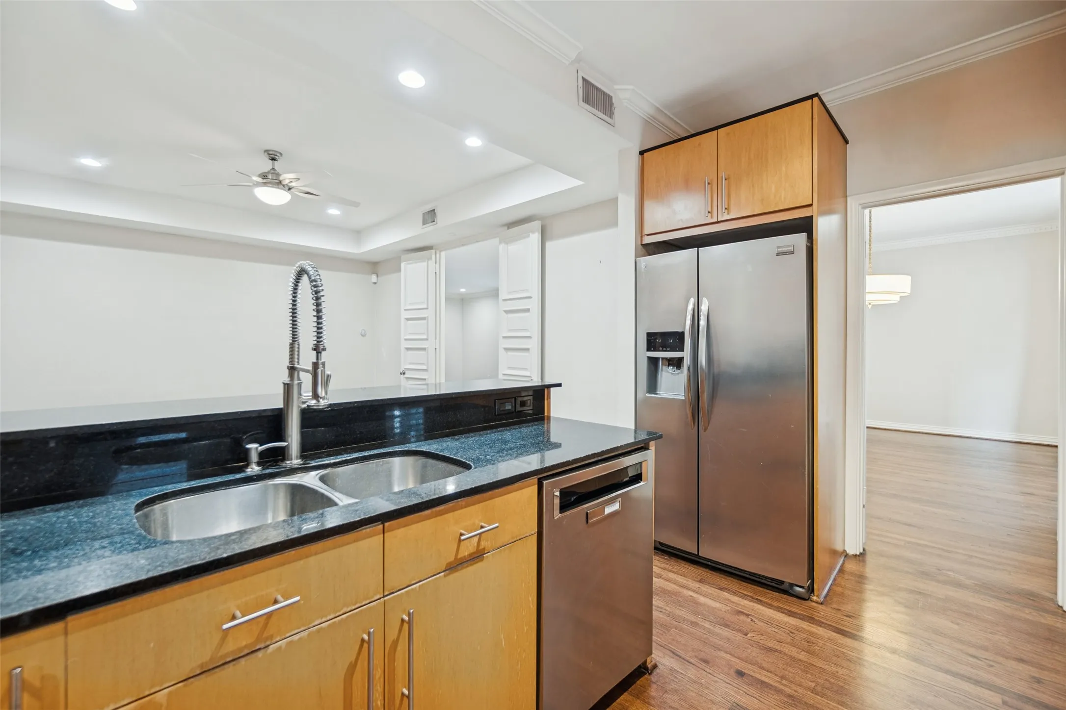 Kitchen featuring a double basin sink, stainless steel appliances, granite countertops, wood-finish cabinetry, and recessed lighting