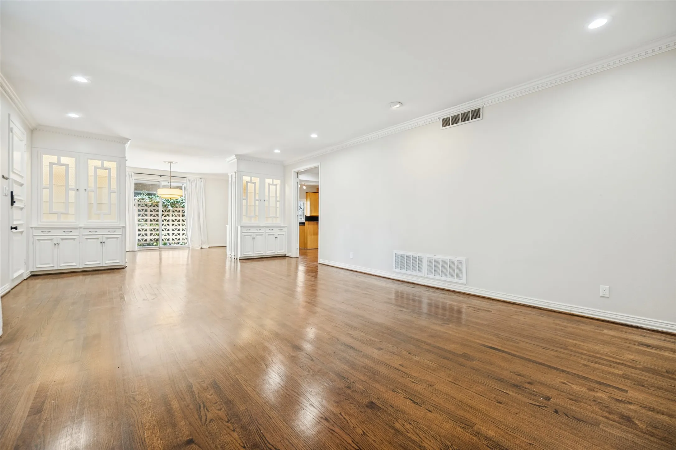 Hardwood flooring, recessed lighting, crown molding, built-in cabinetry, and sliding glass doors