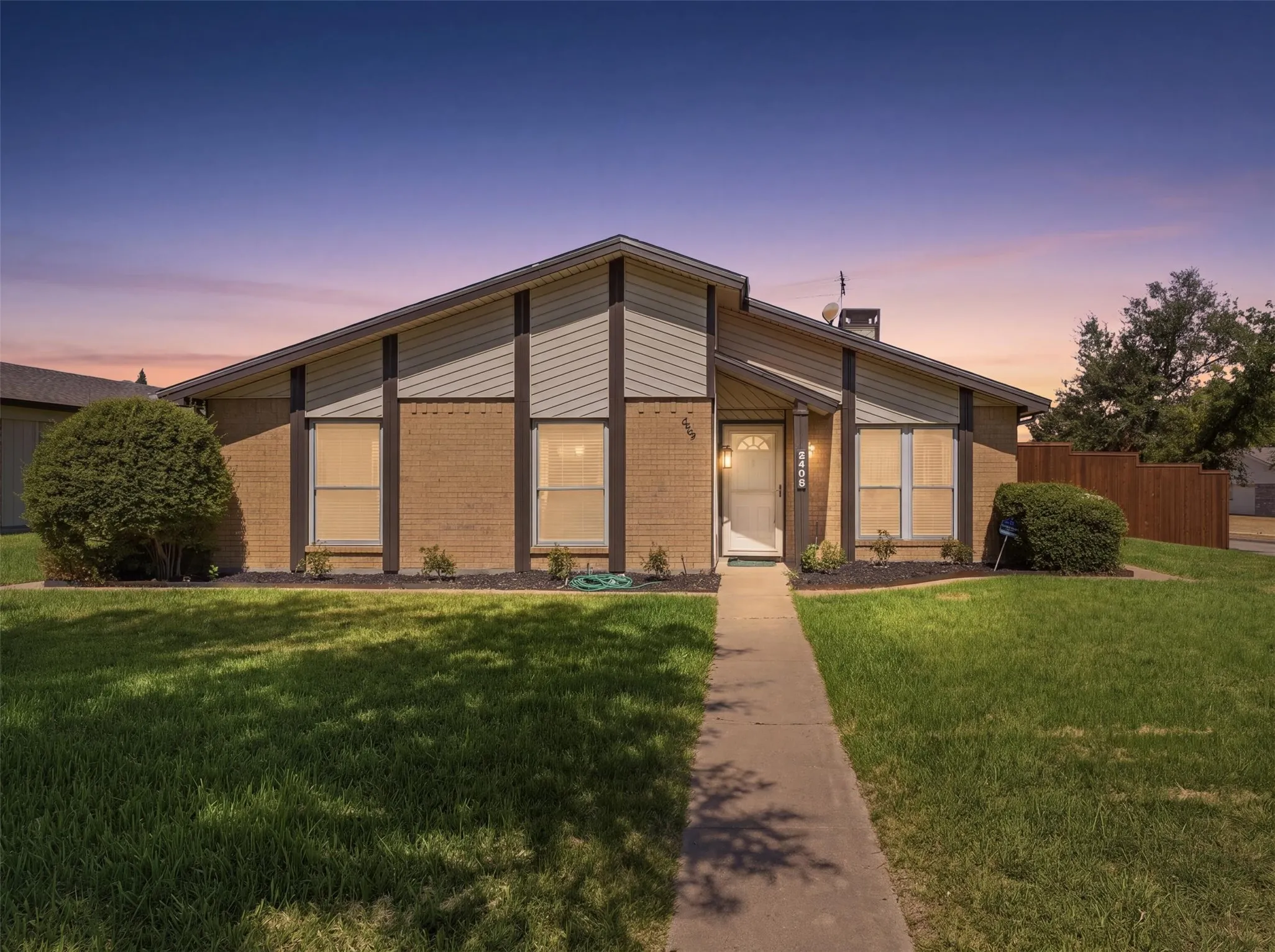 Brick and siding exterior with a pitched roofline, an integrated front porch light, and a concrete pathway