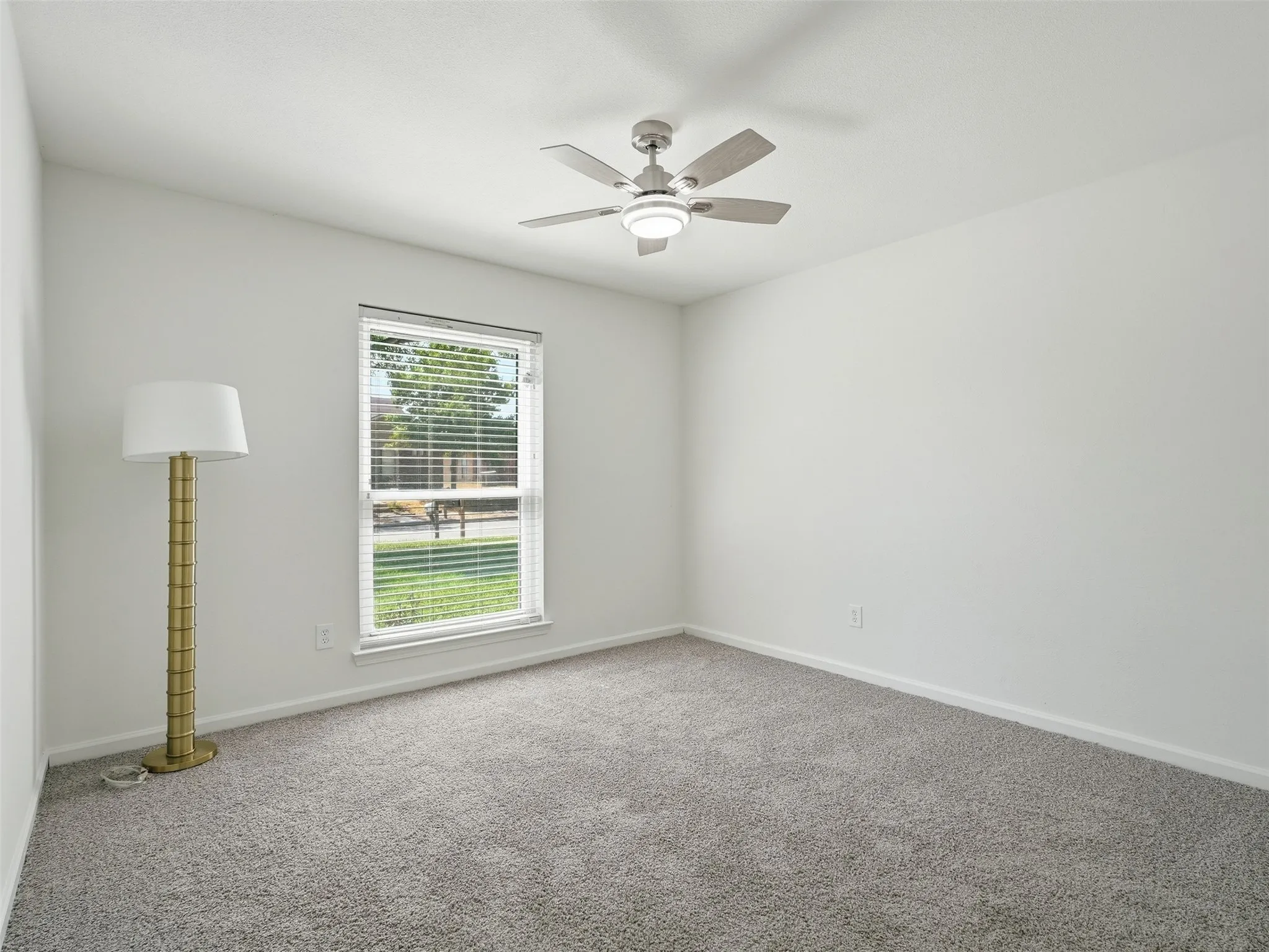 Wall-to-wall carpeting with a neutral finish, a window with horizontal blinds, and a ceiling fan with integrated lighting