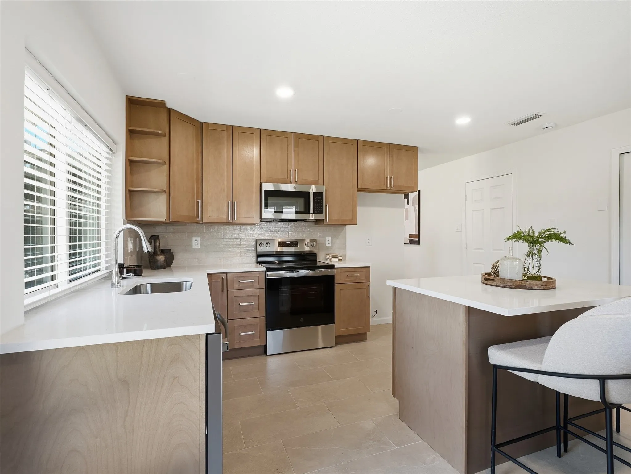 Contemporary kitchen featuring wood-finish cabinetry, stainless steel appliances, and a solid surface countertop