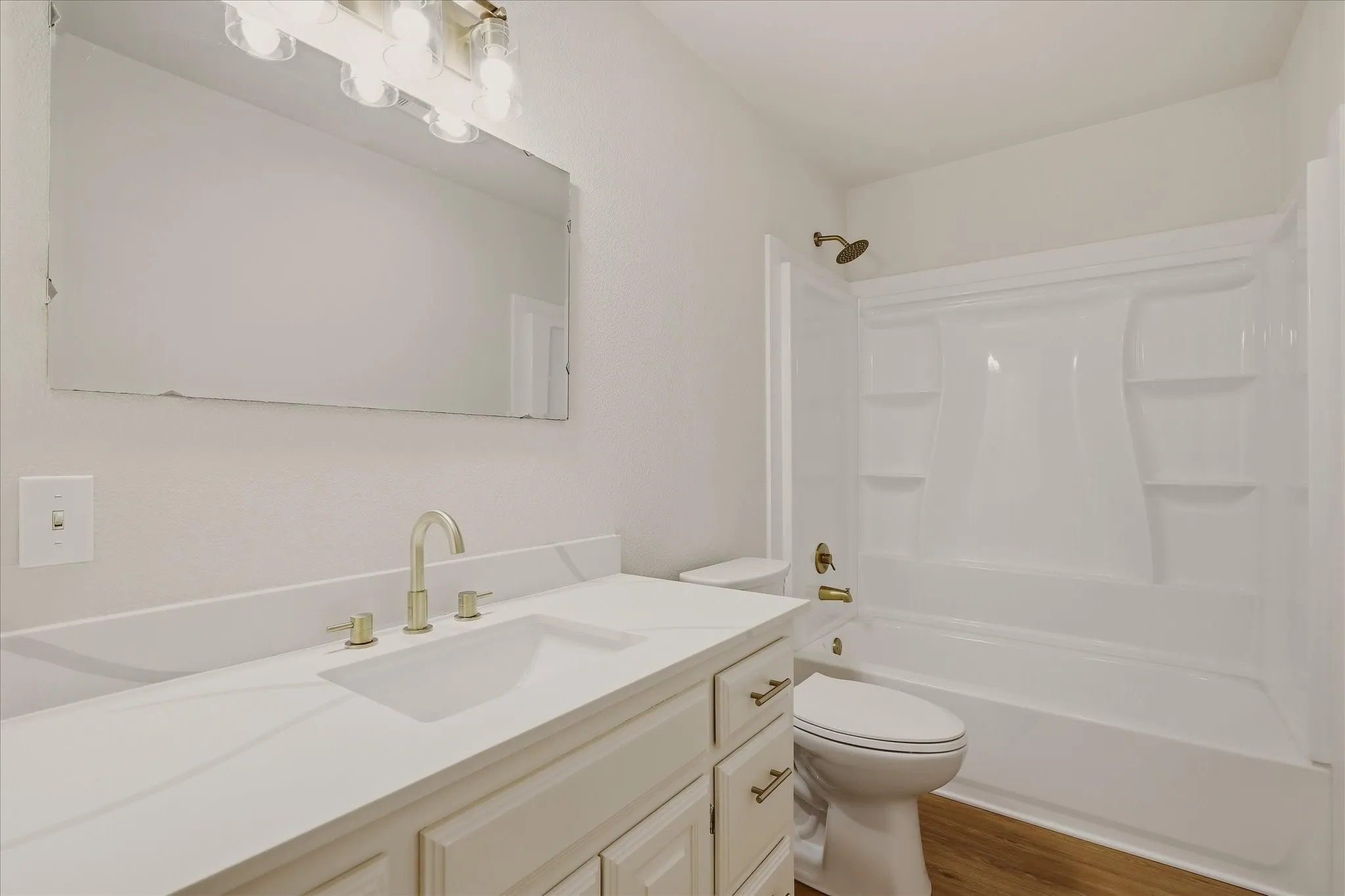 Upstairs hall bathroom, featuring new tub, new vanity, light fixtures, and quartz countertop. More storage cabinets to the left of the vanity, not shown in photo.