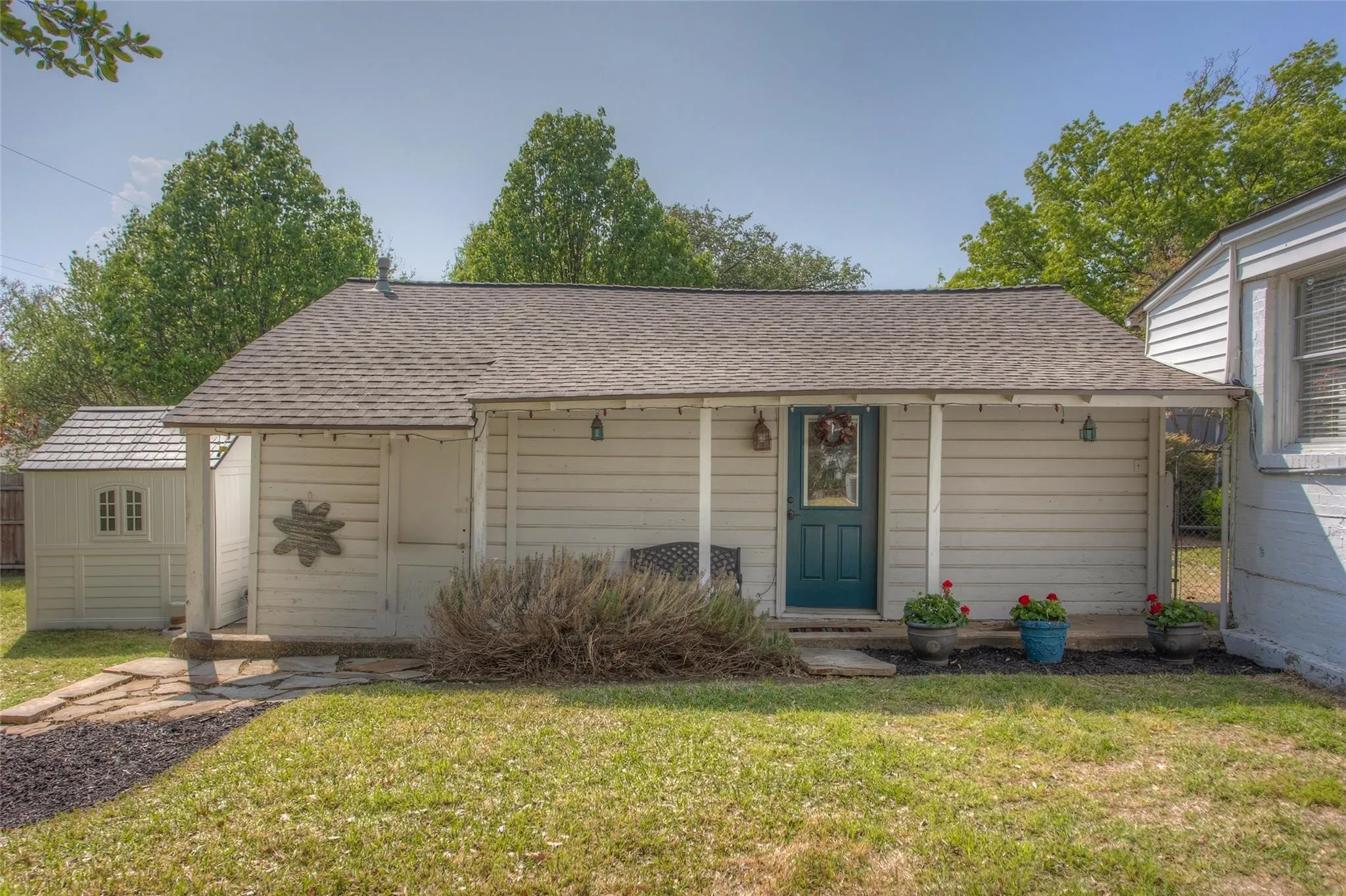 A charming covered porch, pretty blue front door, and potted geraniums welcome you home to your own private retreat.