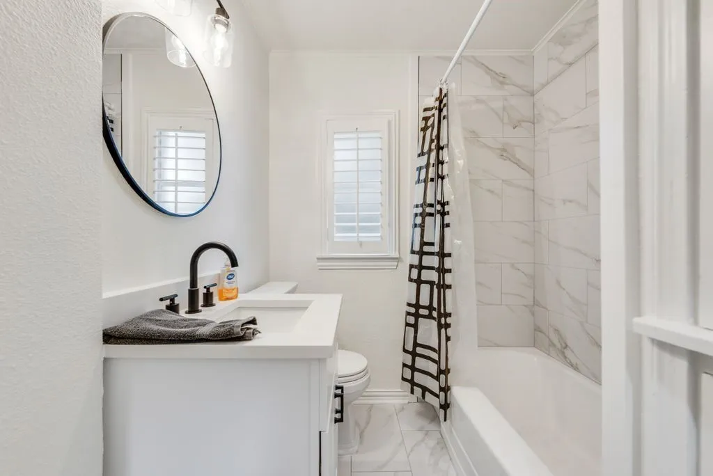 Soak away the day in the full tub surrounded by marble look tile, with plantation shutters for privacy and soft light.