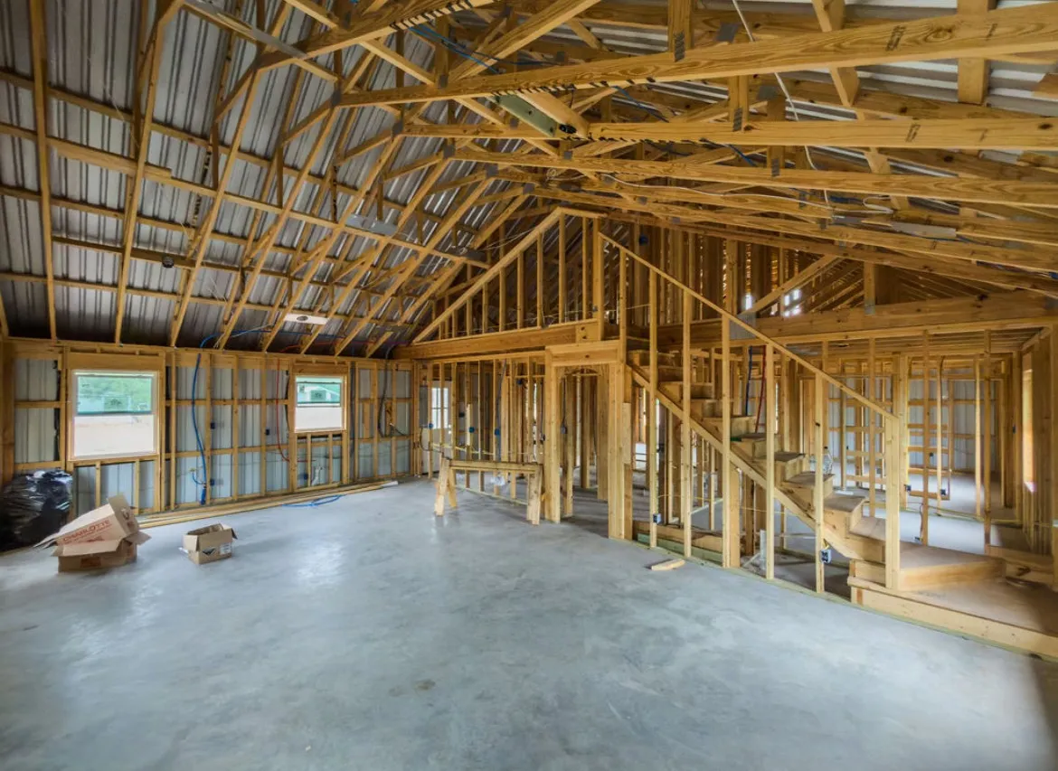Open framed interior with visible wood structural elements, concrete flooring, and exposed corrugated metal ceiling