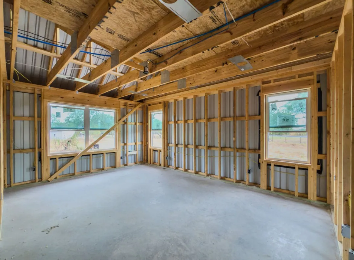 Unfinished interior space featuring exposed wood framing, multiple windows, and a concrete floor
