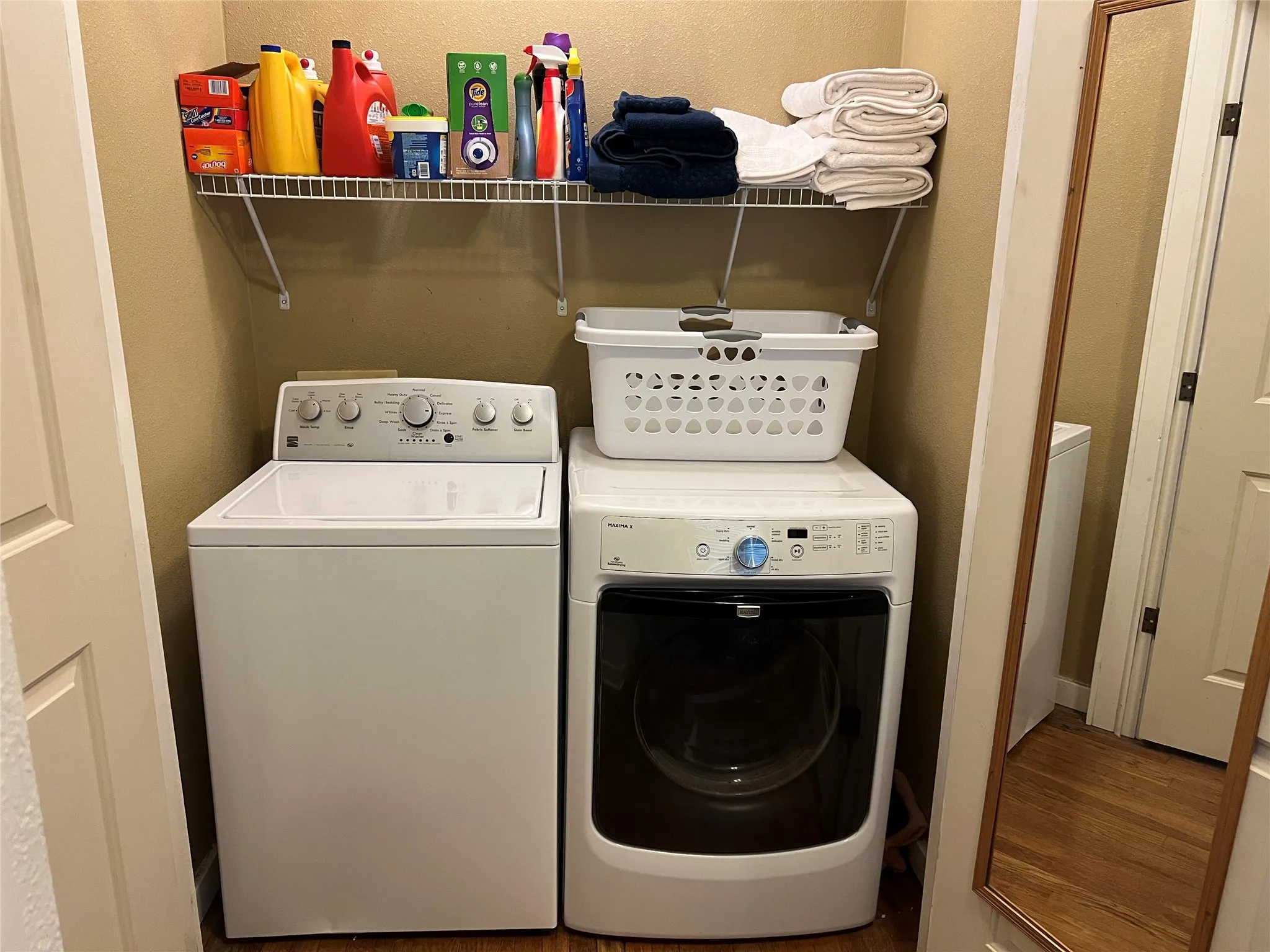 Laundry area featuring separate washer and dryer, a textured wall, and wood finished floors