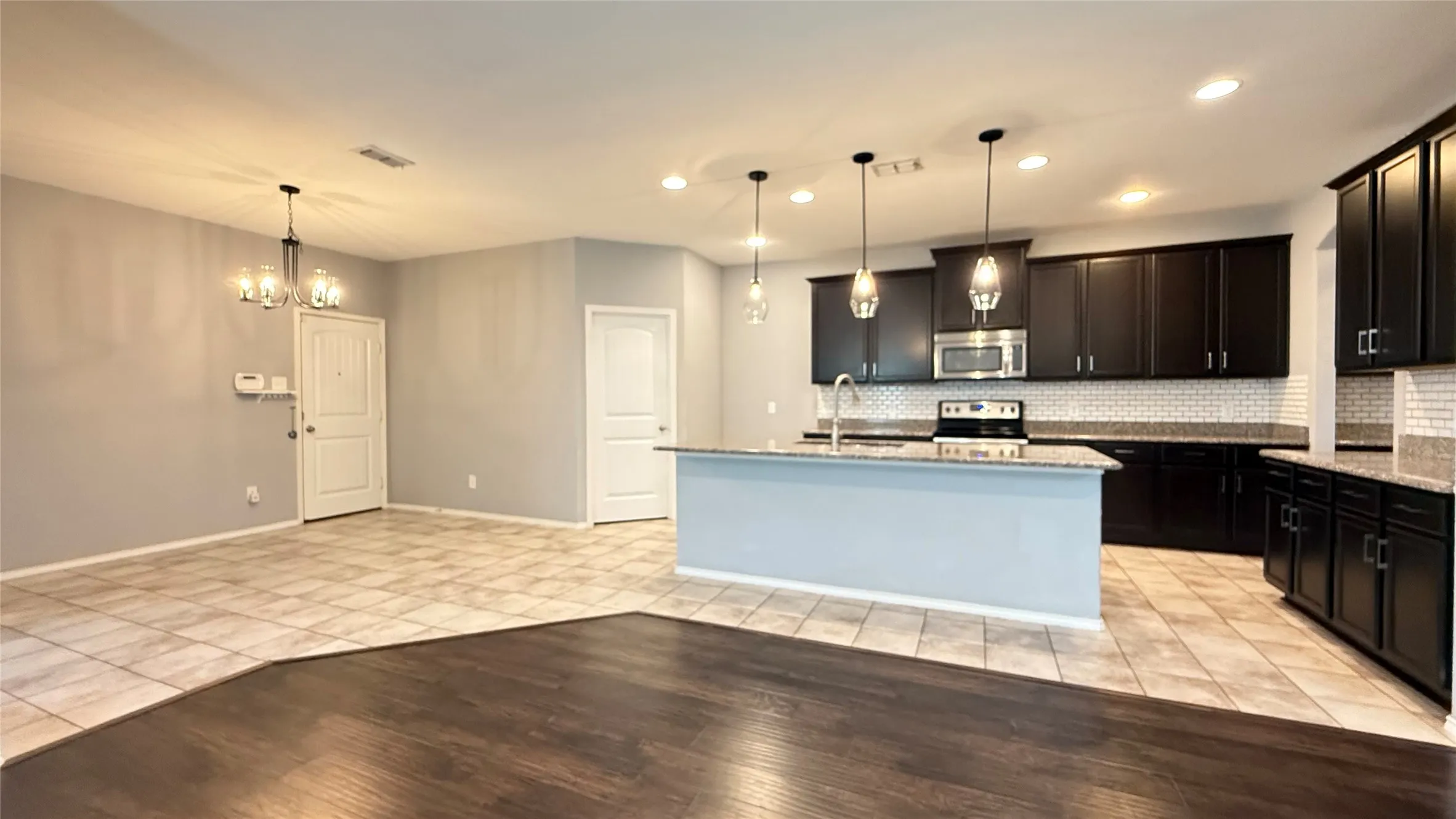 Kitchen with stainless steel appliances, light tile patterned floors, tasteful backsplash, light stone countertops, and recessed lighting