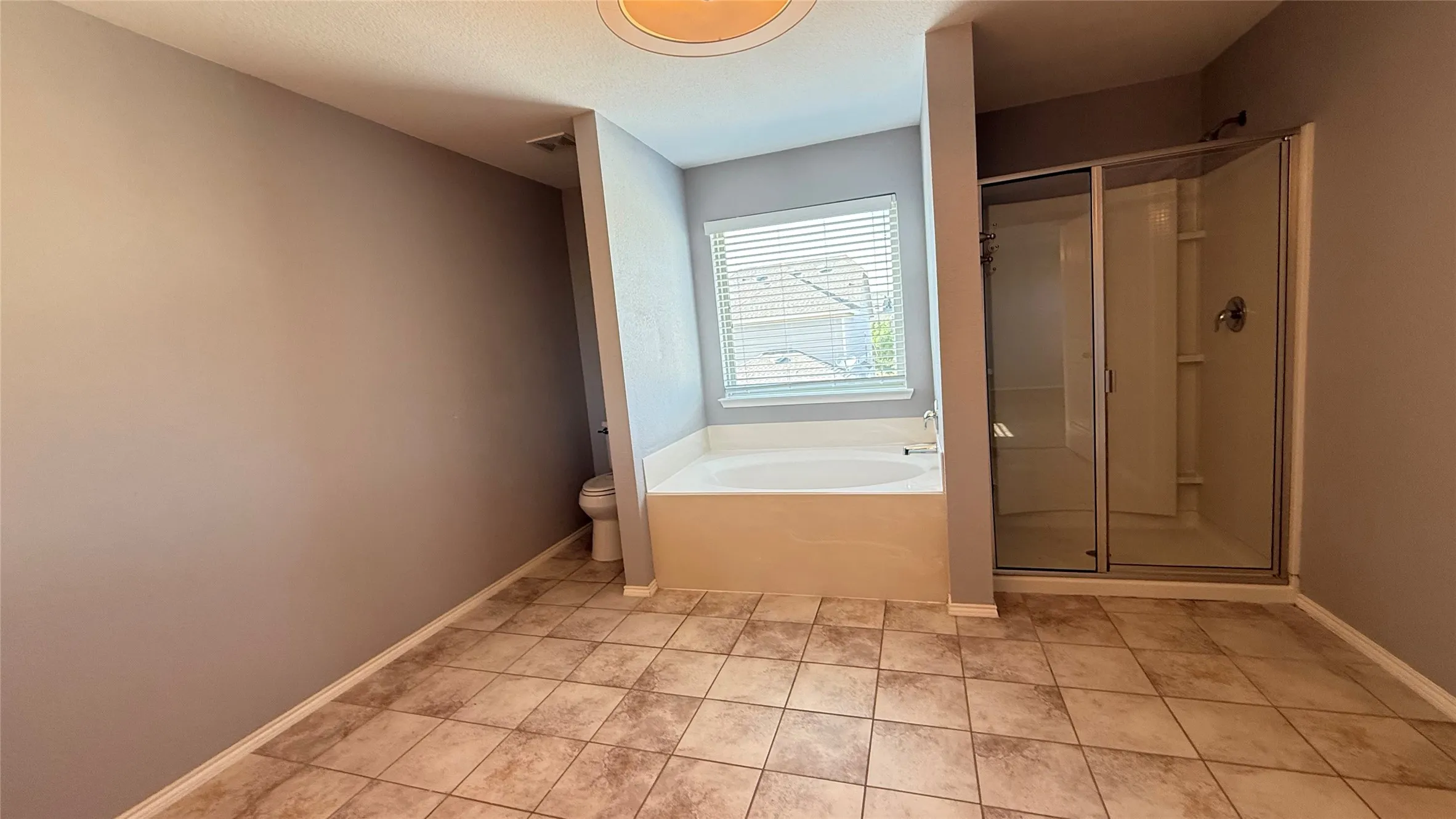 Full bath featuring a garden tub, a stall shower, toilet, baseboards, and tile patterned flooring