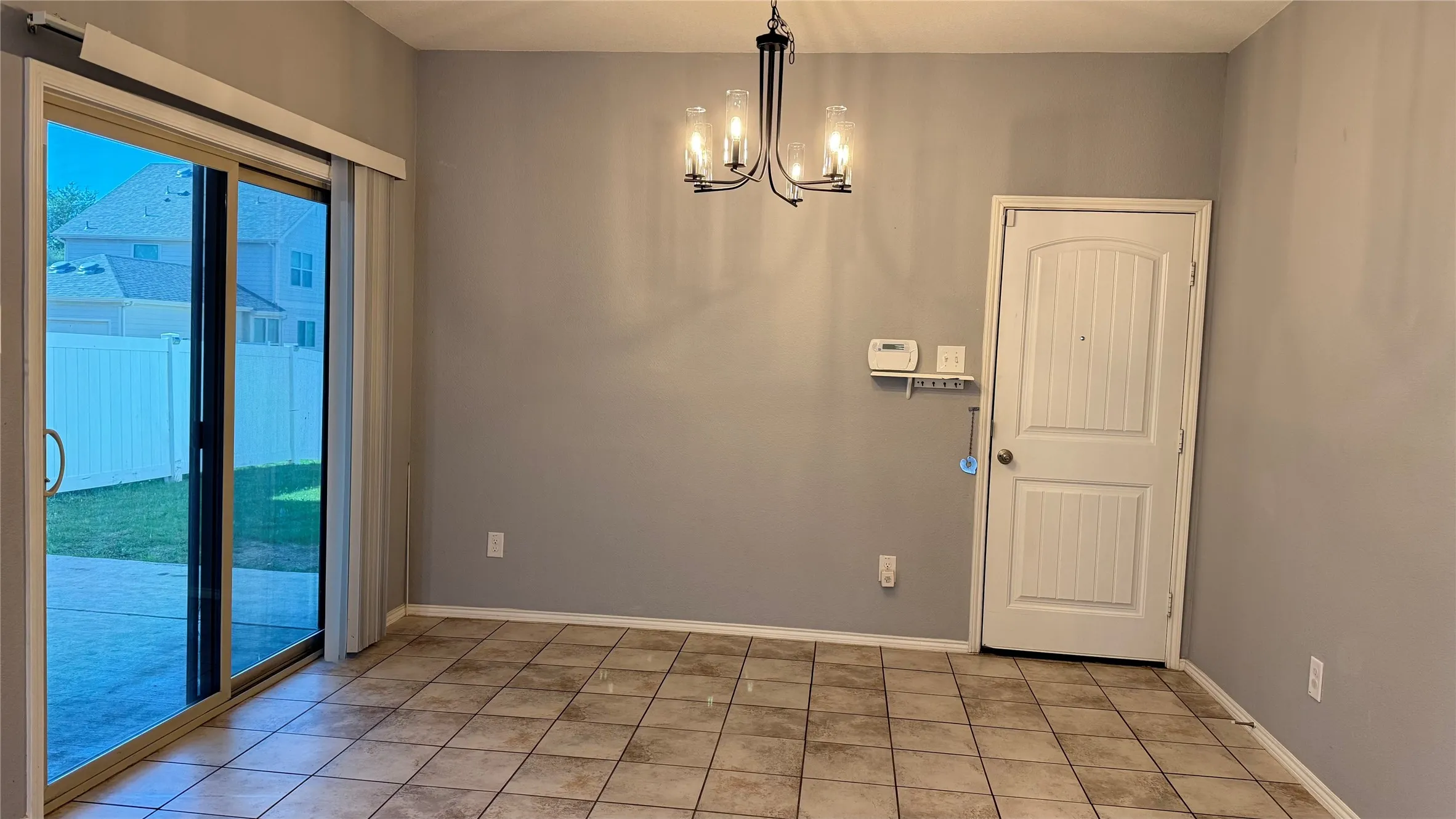 Spare room with a chandelier, baseboards, and light tile patterned floors