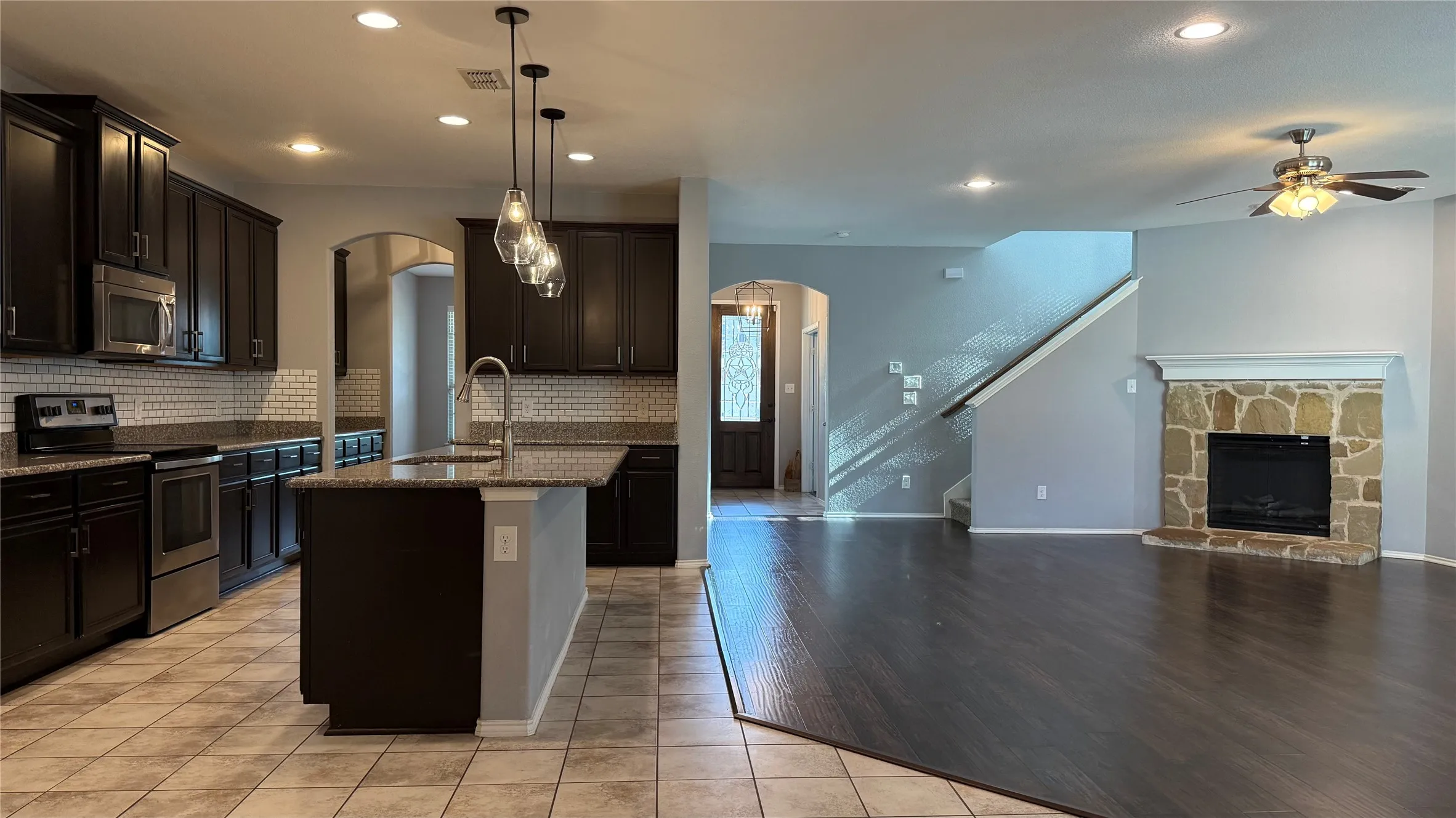 Kitchen featuring stainless steel appliances, arched walkways, open floor plan, dark stone countertops, and recessed lighting